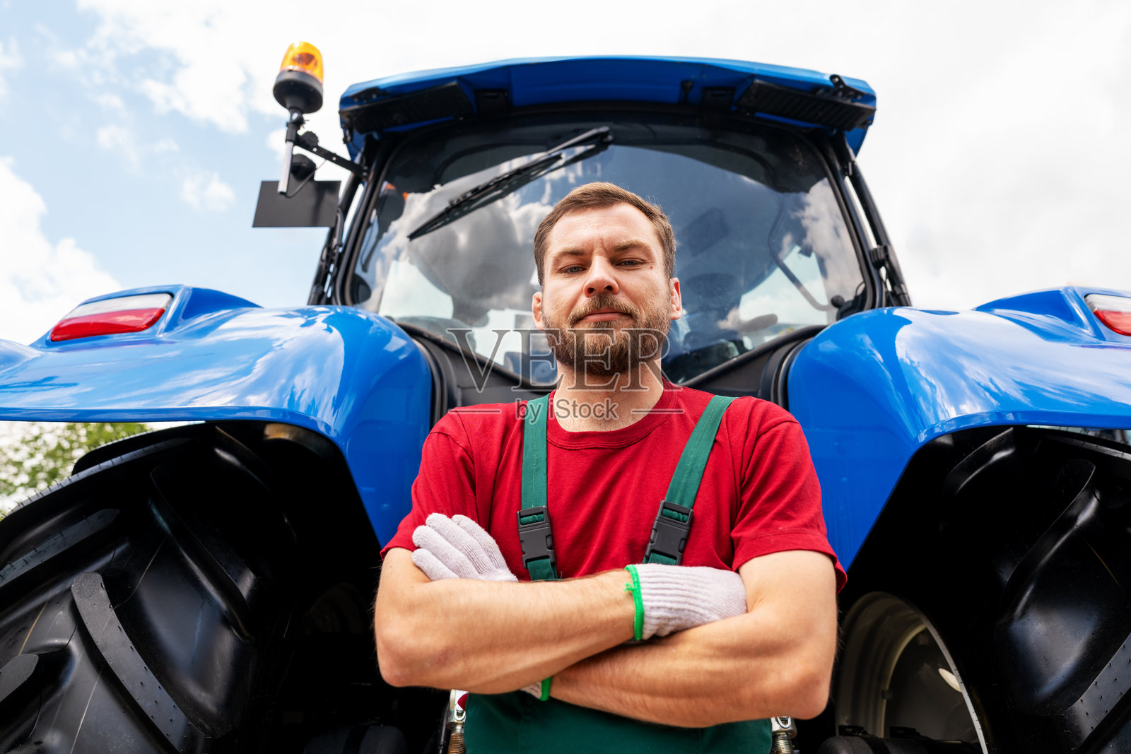 男性农场设备机械师在农场里，站在拖拉机旁照片摄影图片