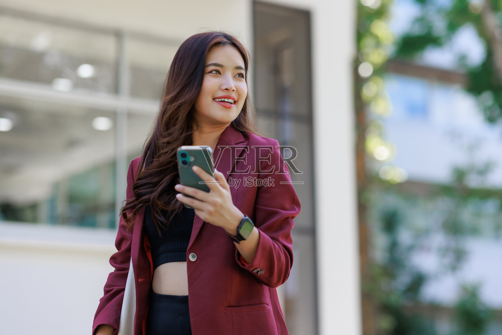 年轻亚洲女性在户外微笑地拿着手机照片摄影图片