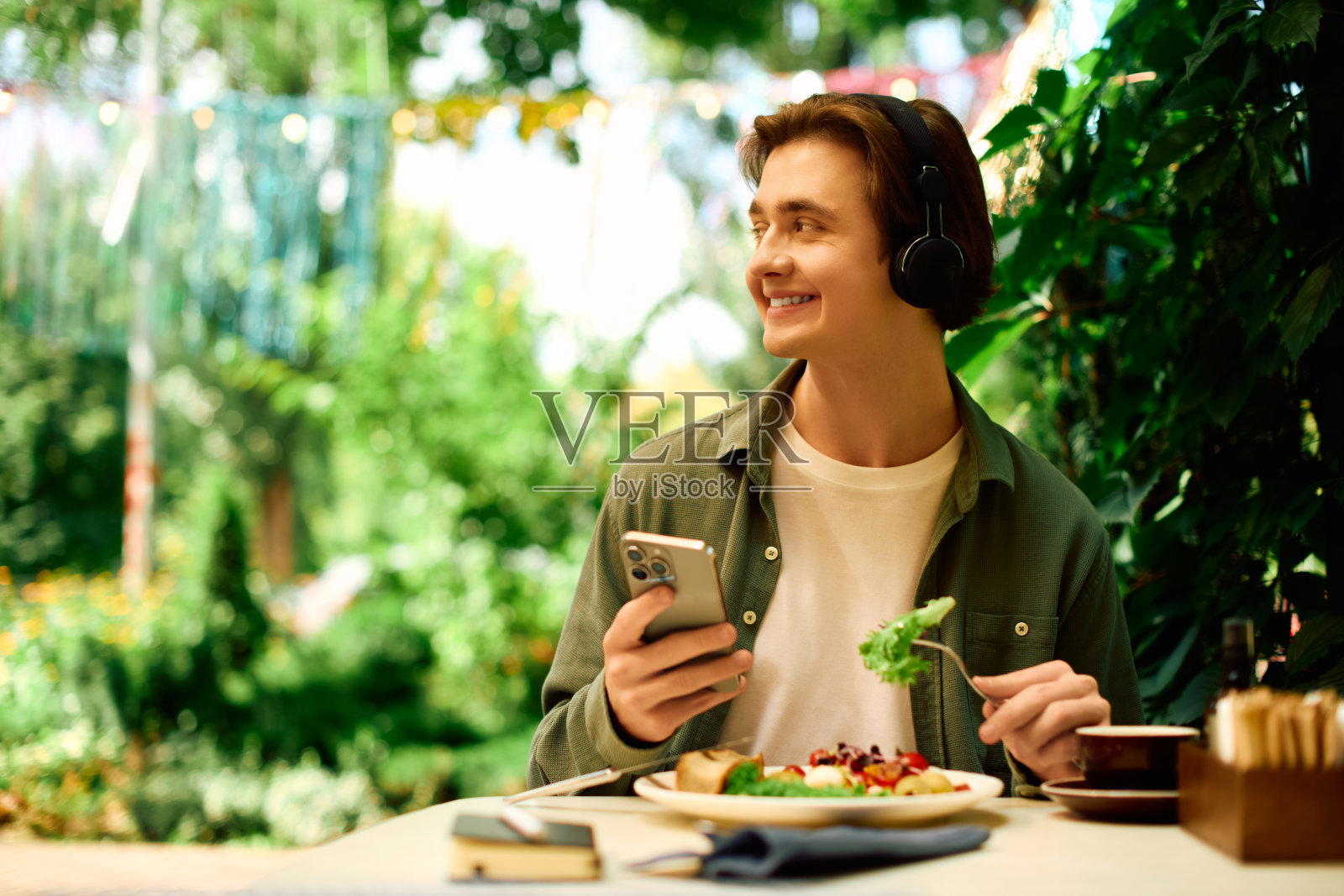 年轻男子在现代咖啡馆享用美食，周围环绕着自然美景照片摄影图片