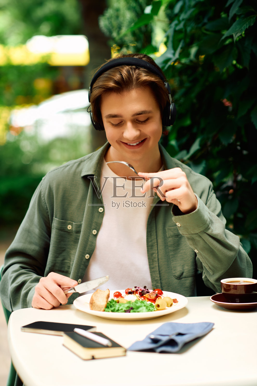 年轻男子在绿意盎然的现代咖啡馆享用美味餐点照片摄影图片