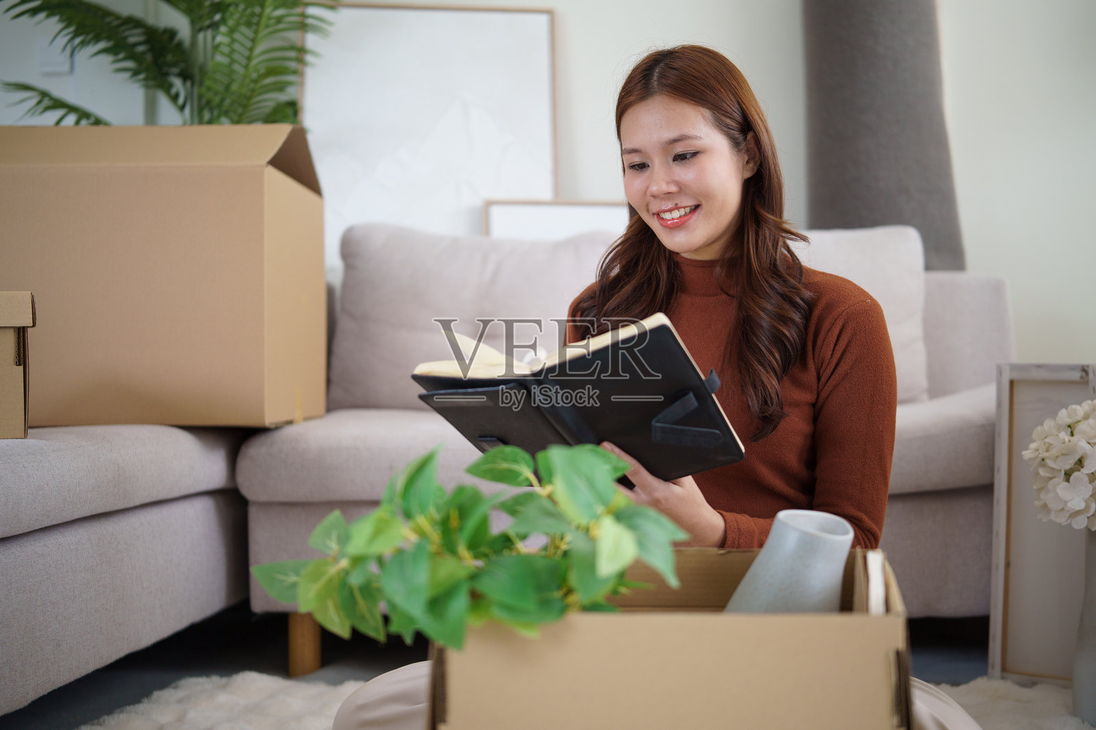 快乐的女房主在搬家日整理物品，并抽出时间查看她的日记。照片摄影图片