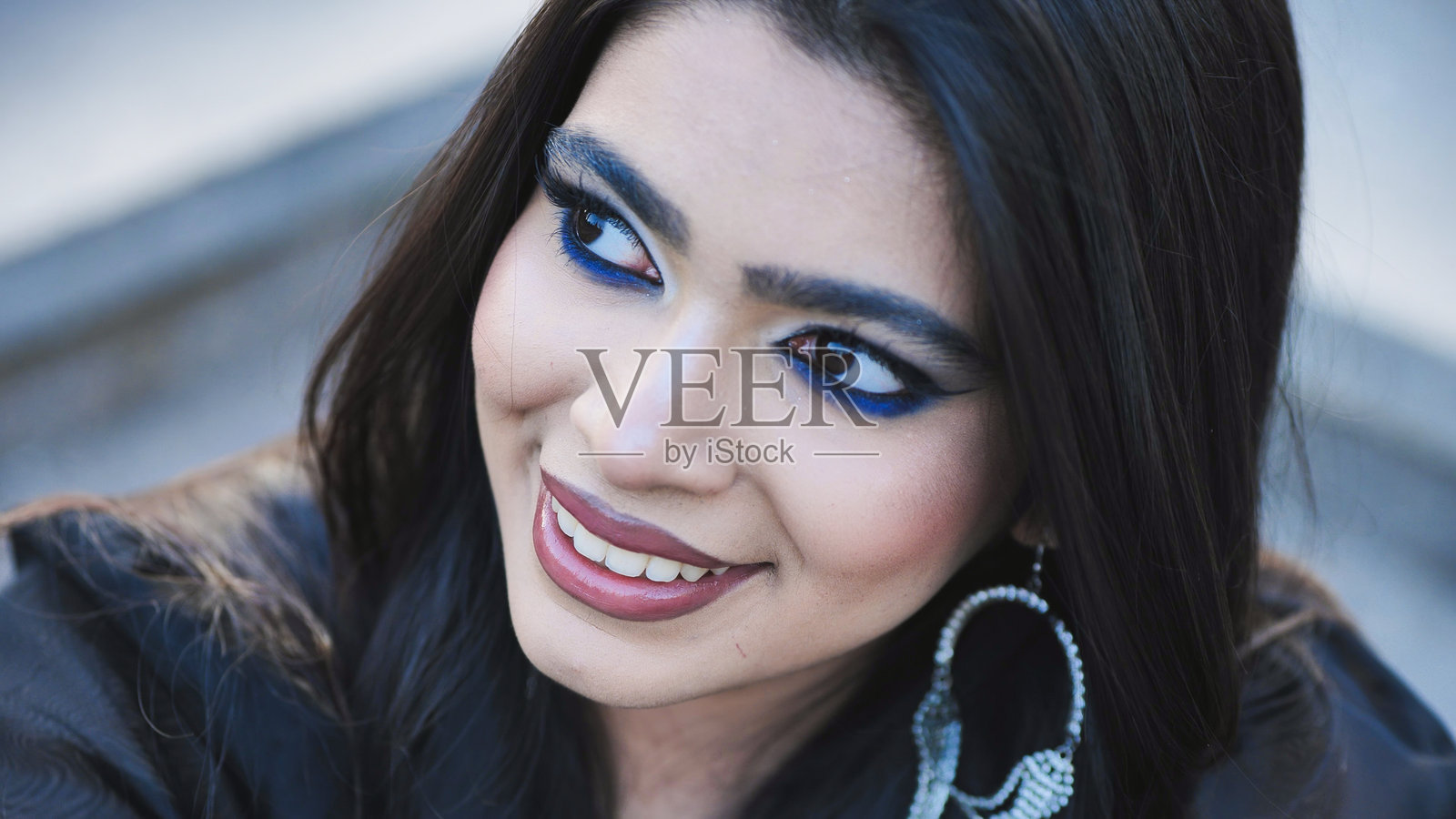 一位孟加拉女子在莫斯科，化着蓝色眼妆，戴着耳环，微笑着看向远方照片摄影图片