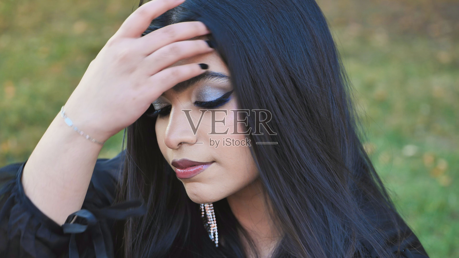 年轻的孟加拉国女性在莫斯科户外公园里整理头发，妆容精致照片摄影图片