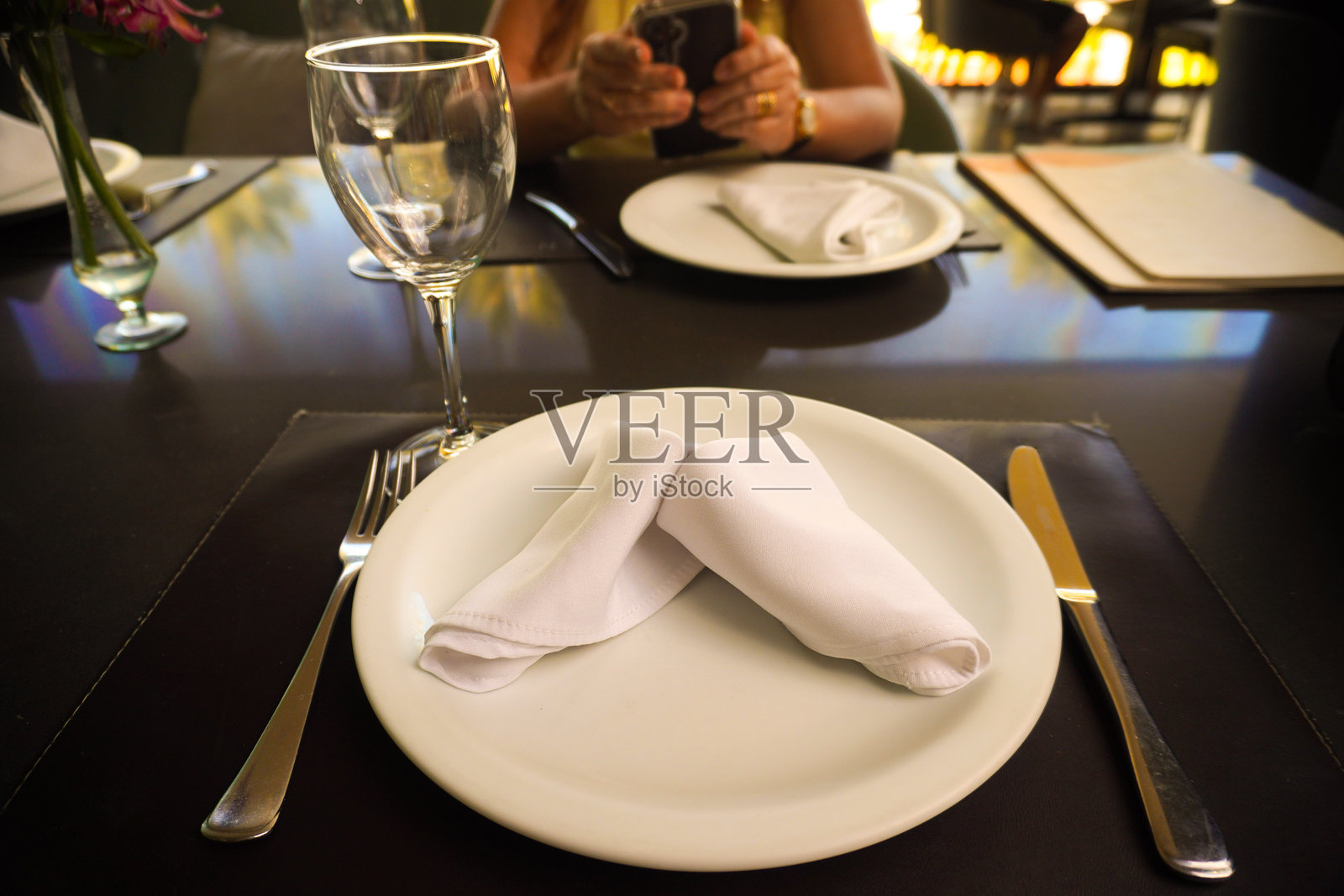 银色餐具和白盘子摆放在餐桌上。照片摄影图片