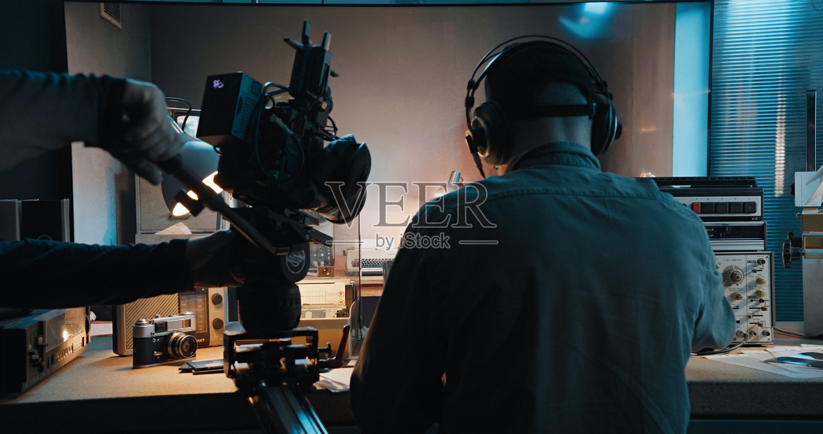 间谍或战争电影的幕后花絮。摄像师正在拍摄一名演员假装通过无线电系统进行通信的场景。照片摄影图片