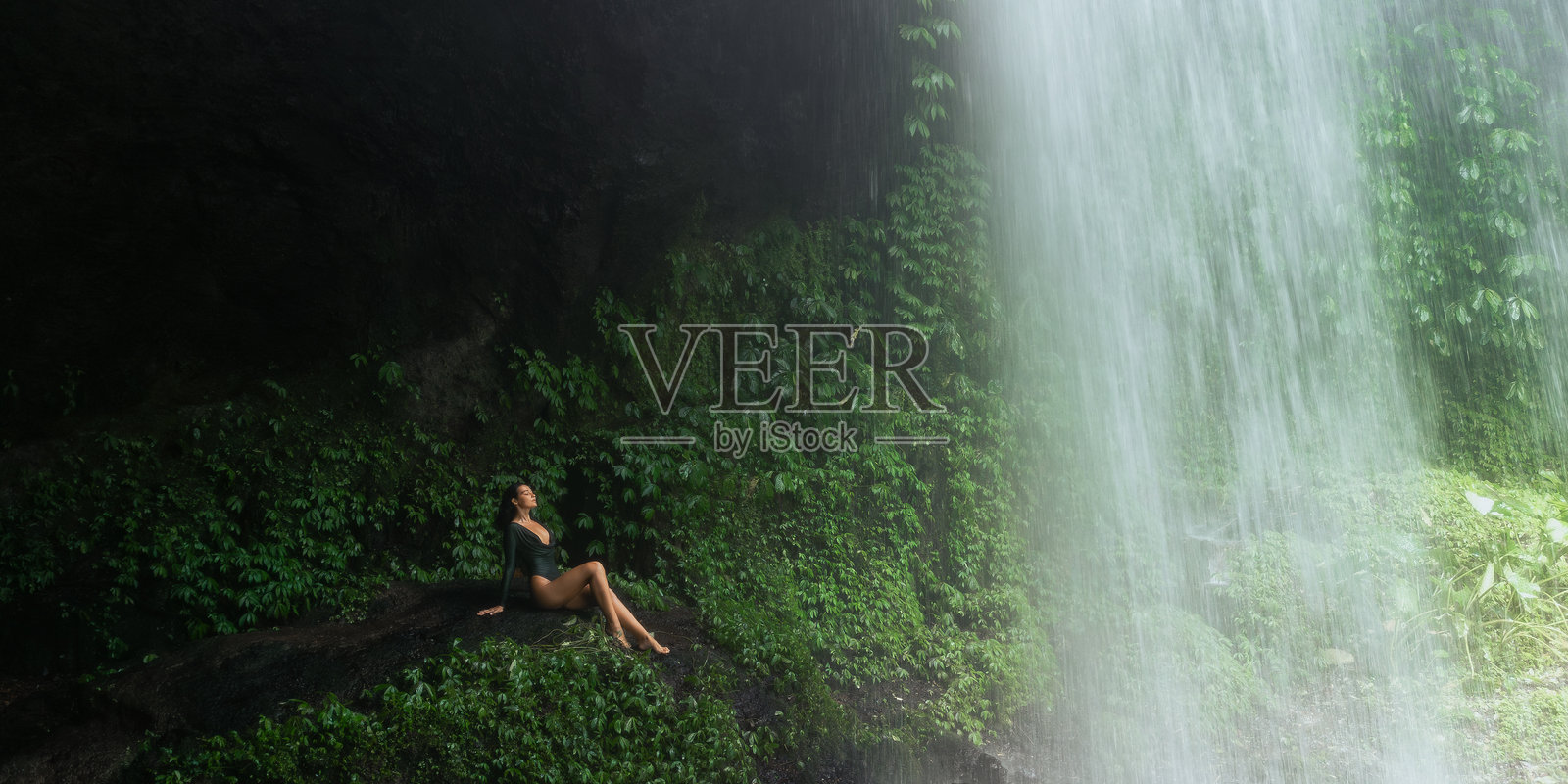 女游客在瀑布后享受隐秘的丛林瀑布照片摄影图片