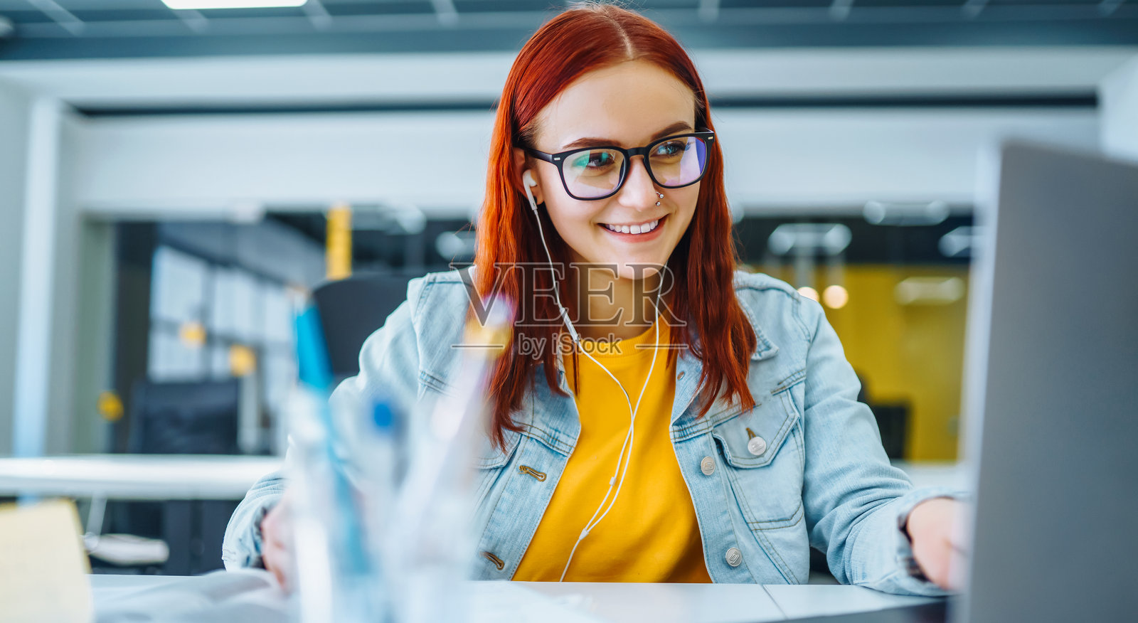 阳光明媚的一天，一位年轻女子在共享办公空间用笔记本电脑工作。照片摄影图片