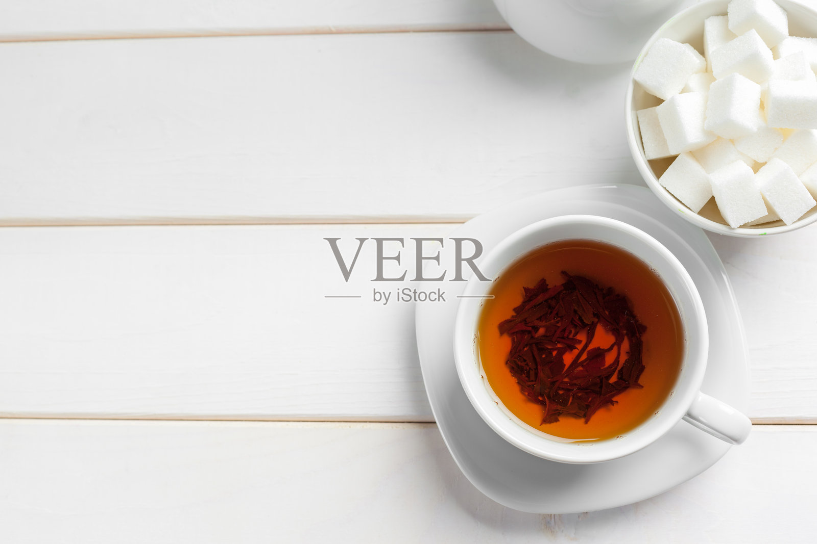 下午，在家里的木桌上，享受一杯加方糖的茶照片摄影图片