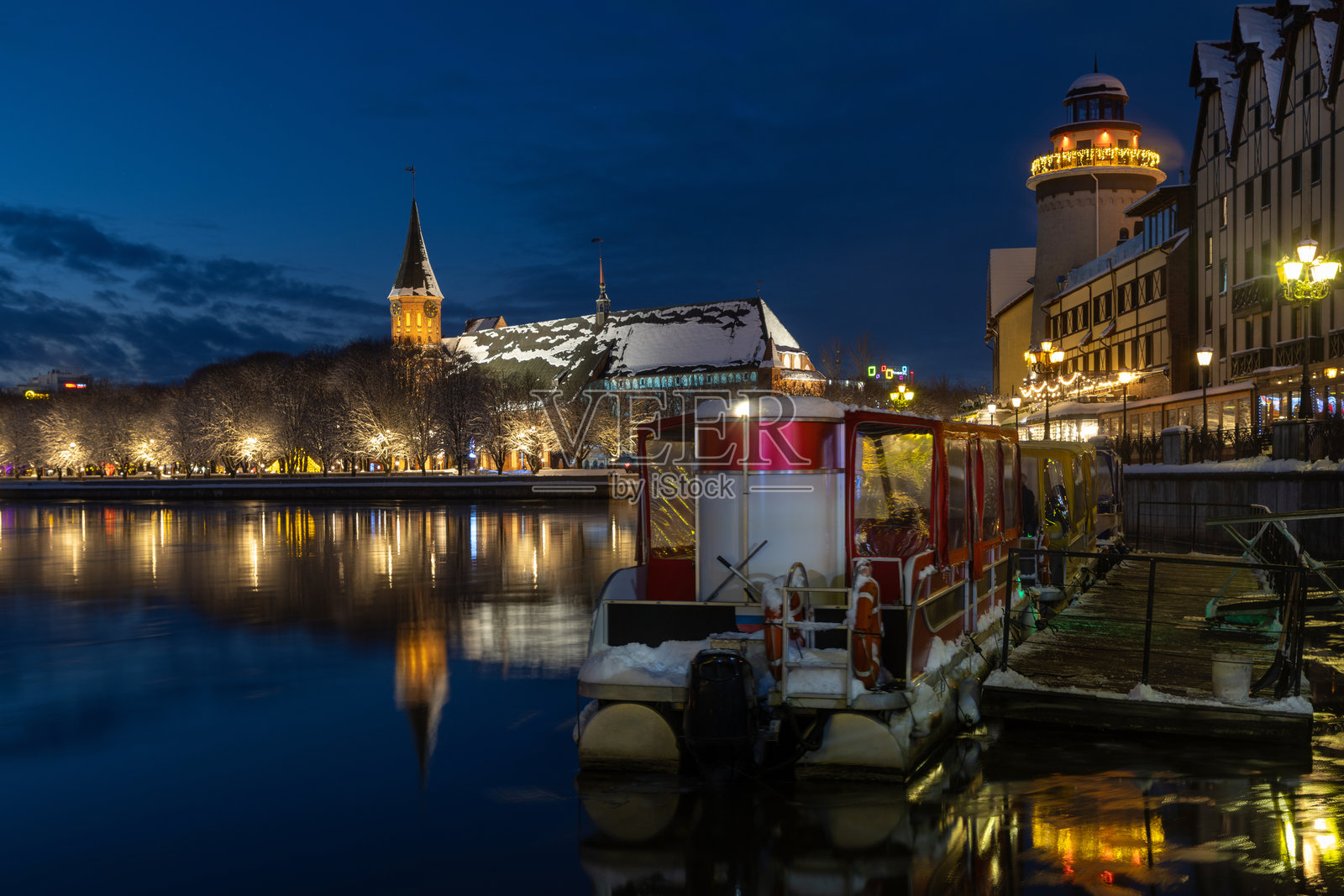 傍晚时分，游船在河上，倒影清晰，背景是渔村海滨长廊和主教座堂。照片摄影图片