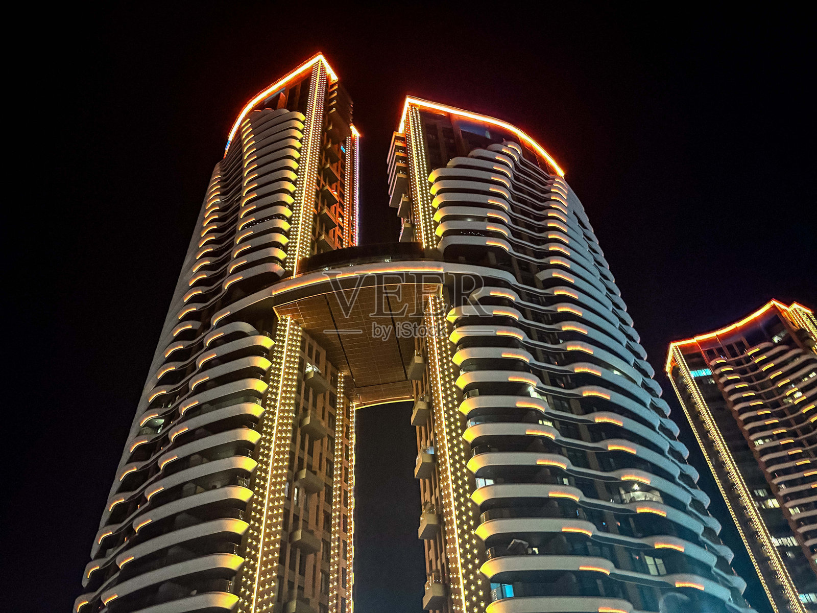 夜间，仰视拍摄的相互连接的摩天大楼，灯火辉煌照片摄影图片