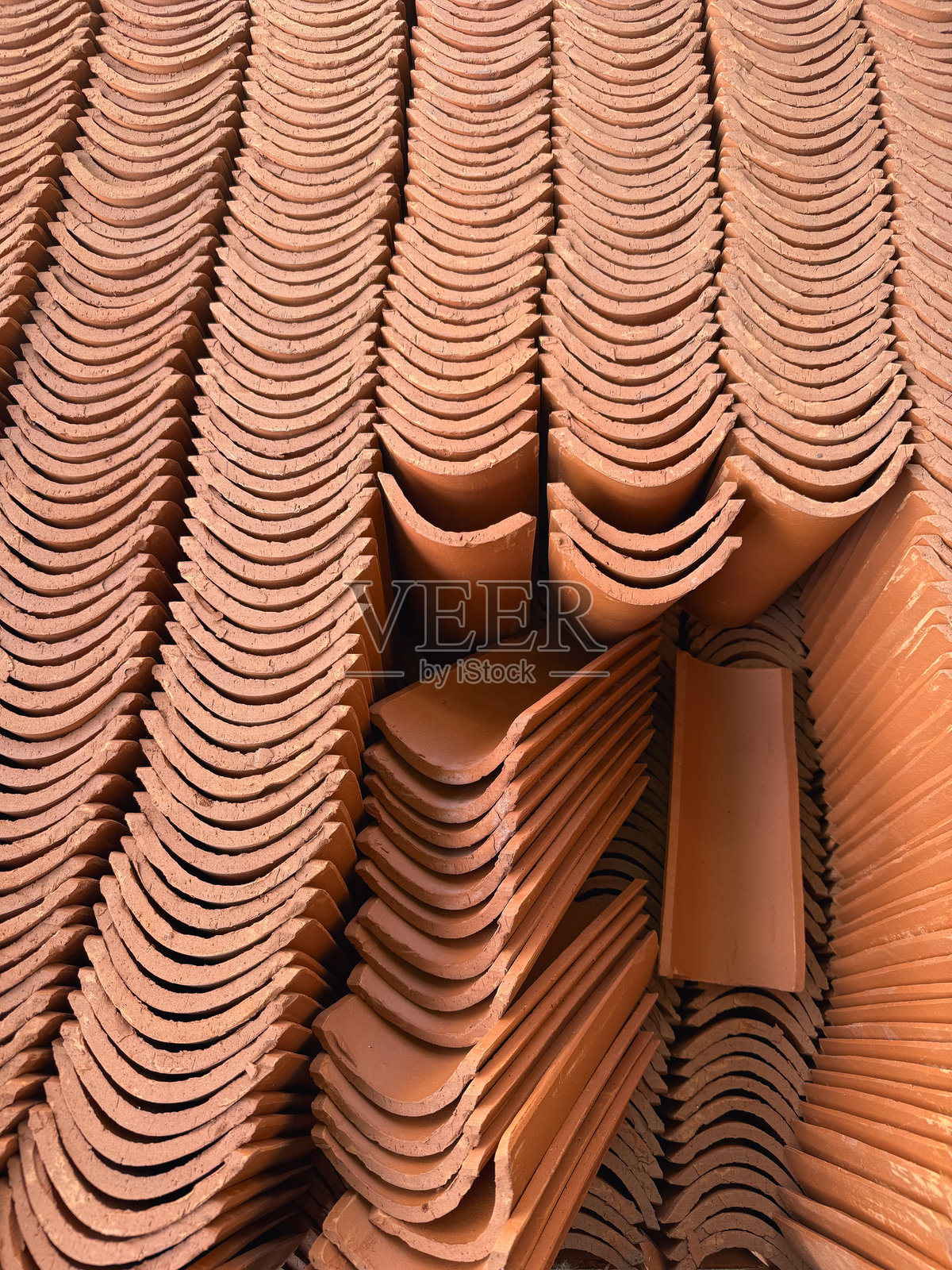 堆叠的红色陶瓦特写，传统的粘土屋顶材料——瓦片图案的俯视背景照片摄影图片