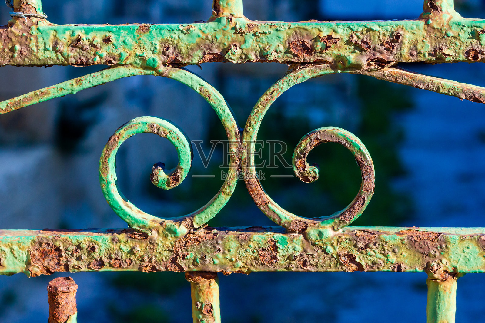 带有装饰性螺旋和风化铜绿的锈蚀绿色铁栏杆照片摄影图片