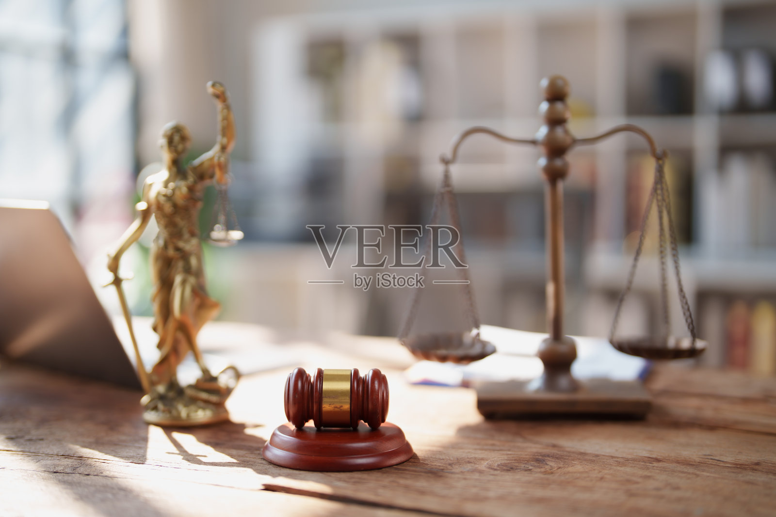 纹理木桌上摆放着法槌、正义女神雕像和天平，象征着律师办公室里的法律判决、公平、道德和司法体系。照片摄影图片