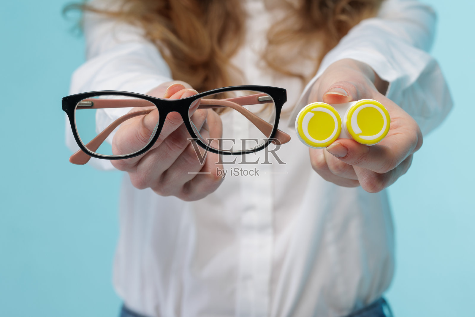 手拿眼镜和隐形眼镜盒，用于视力矫正选择照片摄影图片