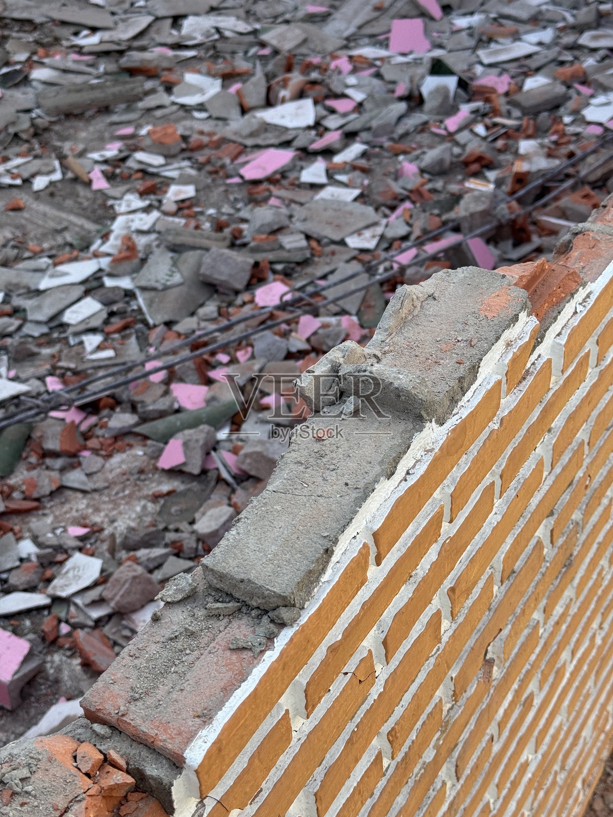 受损的砖墙，带有破碎的混凝土块和散落在地上的瓦砾，展示了建筑工地的拆除碎片和结构损坏。照片摄影图片