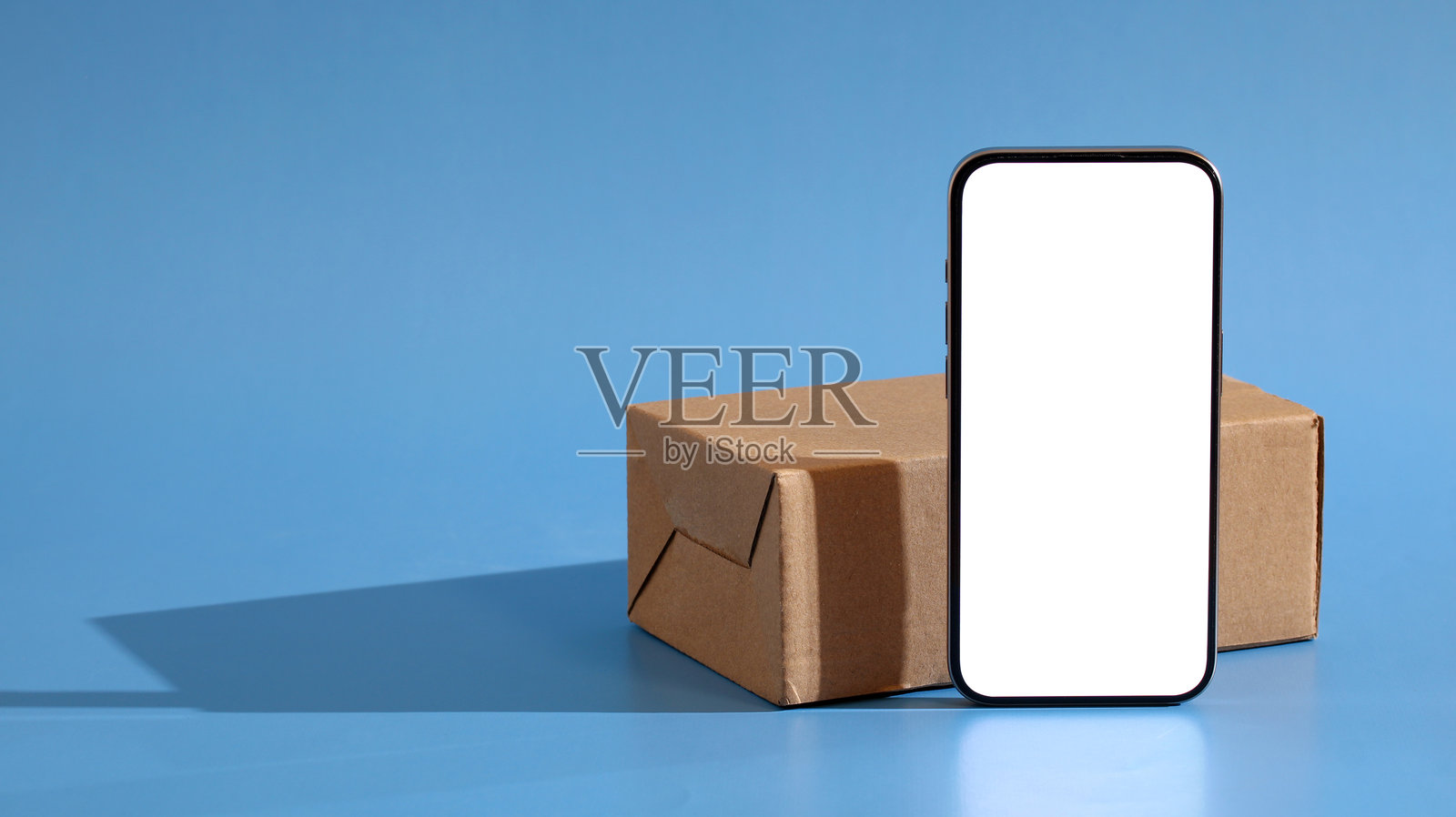 蓝背景上的空屏智能手机和包裹盒照片摄影图片