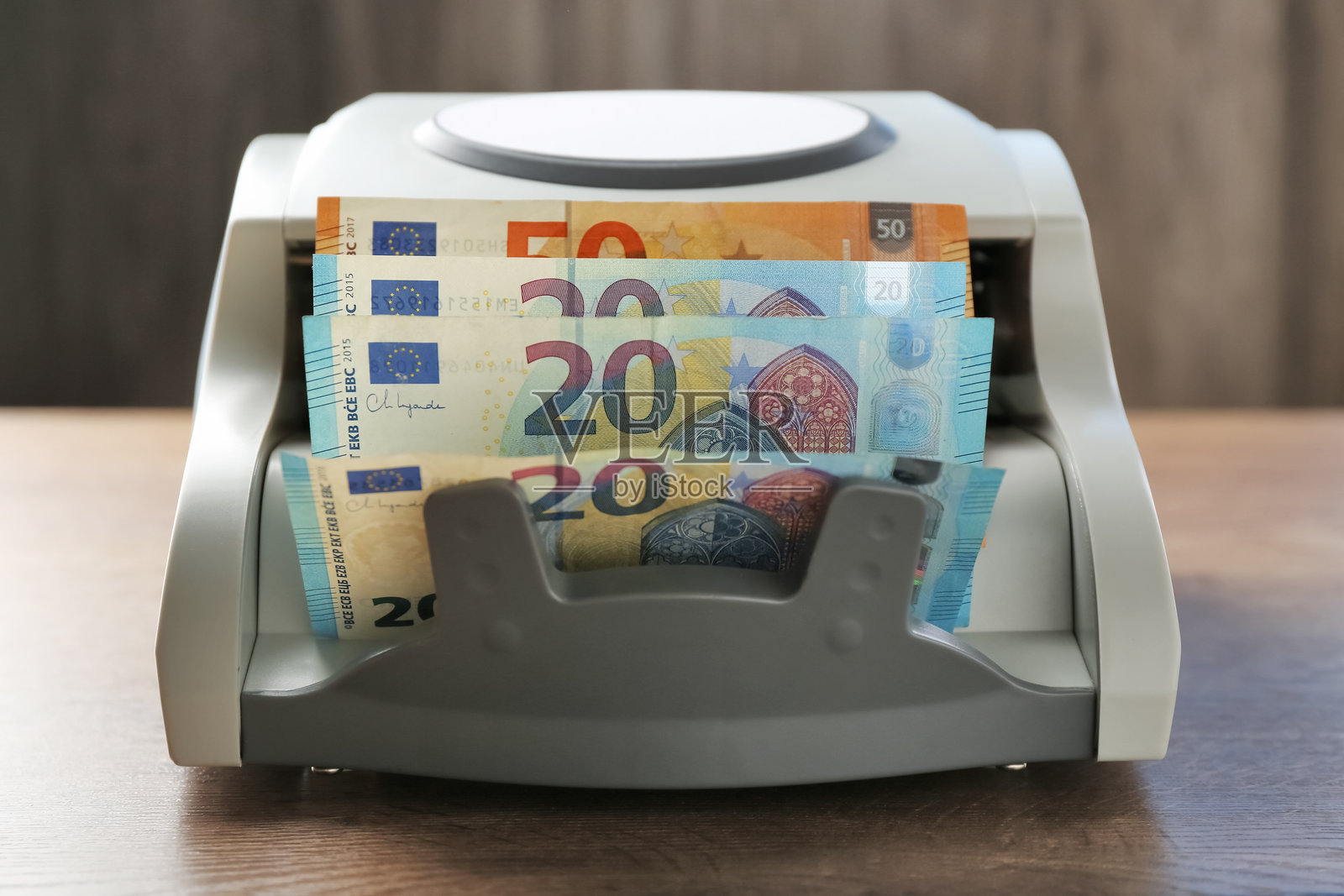 木桌上的点钞机和欧元钞票，特写照片摄影图片