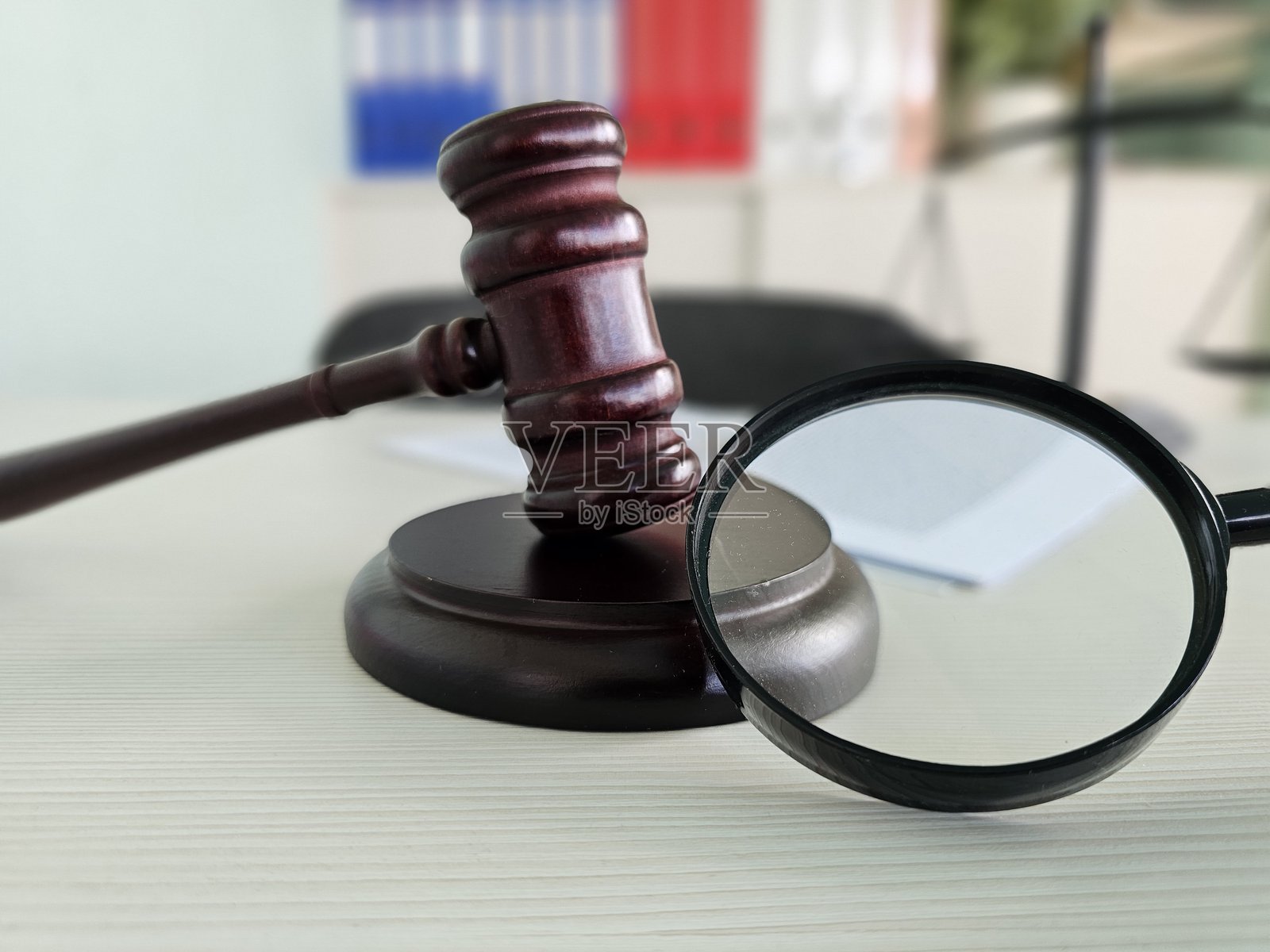 法庭木槌和放大镜放在桌子上，背景是旗帜照片摄影图片