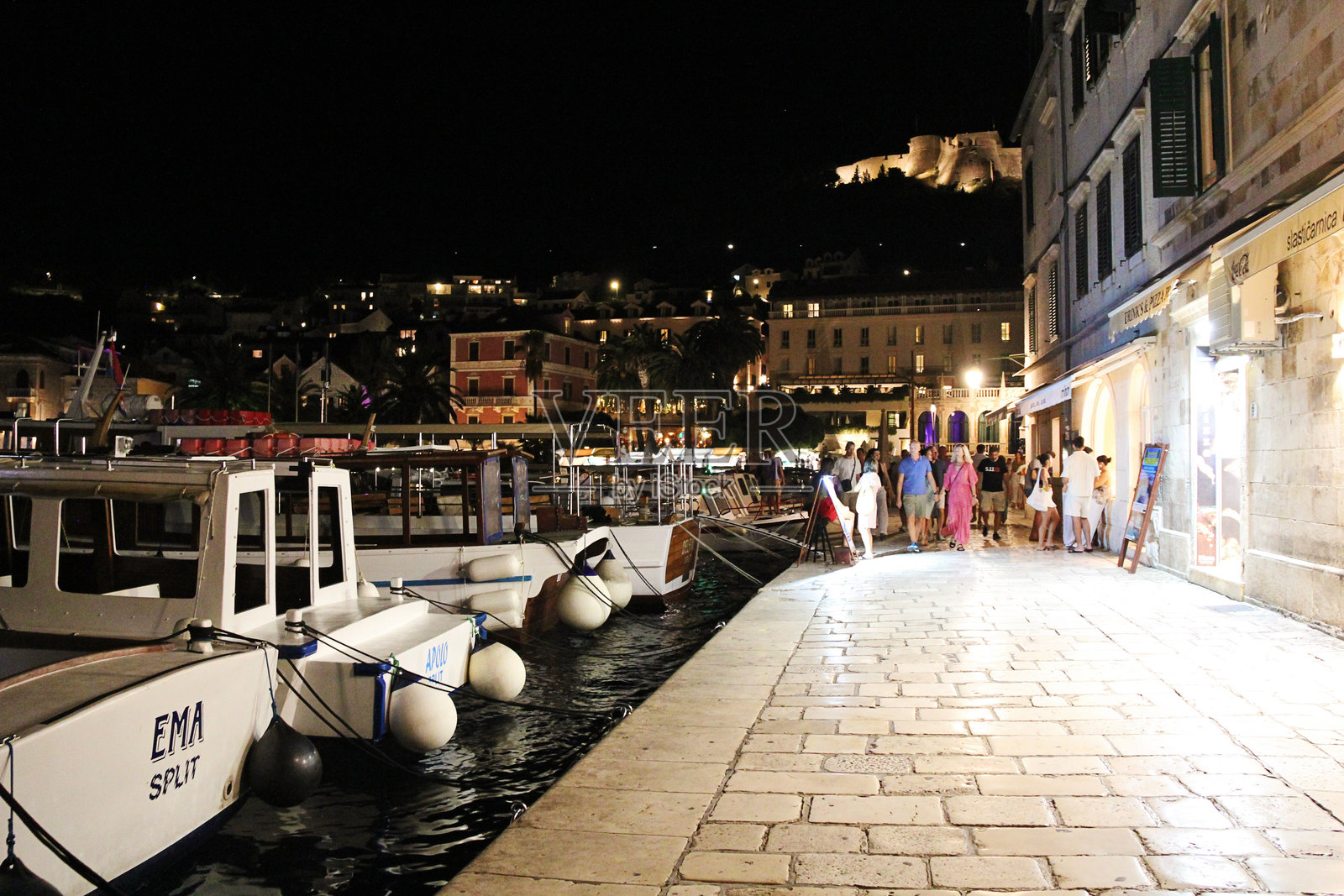 哈瓦尔老城夜晚景色,有城堡、船只和散步的游客照片摄影图片