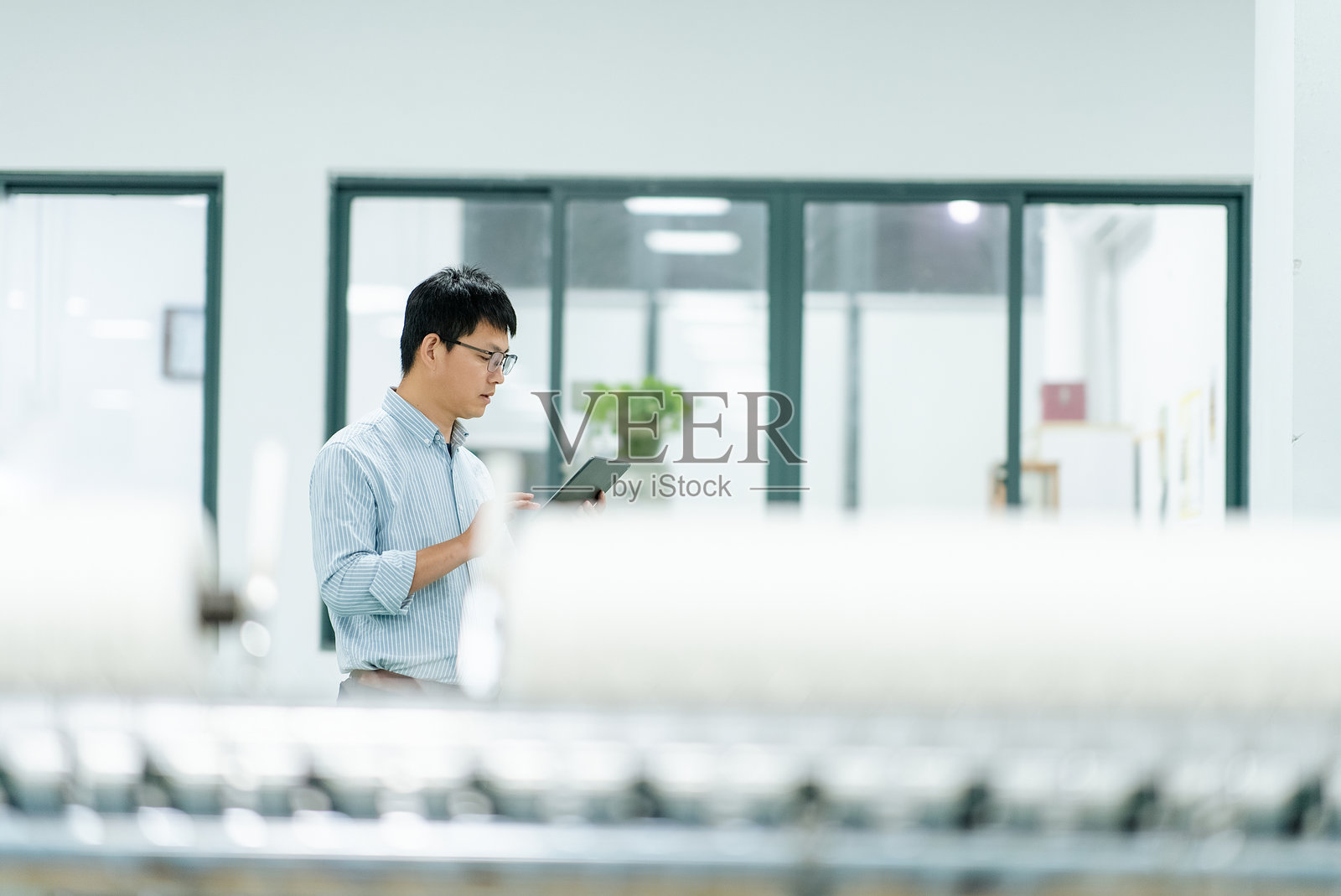 戴眼镜男性工程师在工厂车间使用平板电脑检查设备照片摄影图片