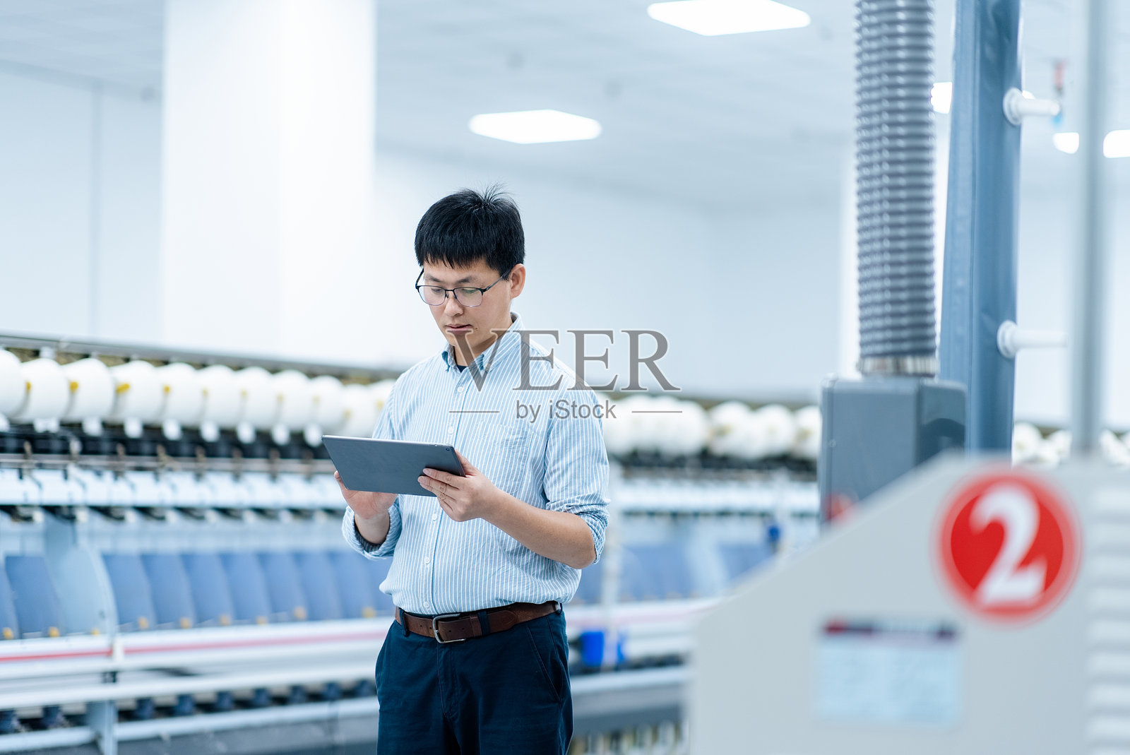 工厂车间内戴眼镜男子手持平板检查设备照片摄影图片