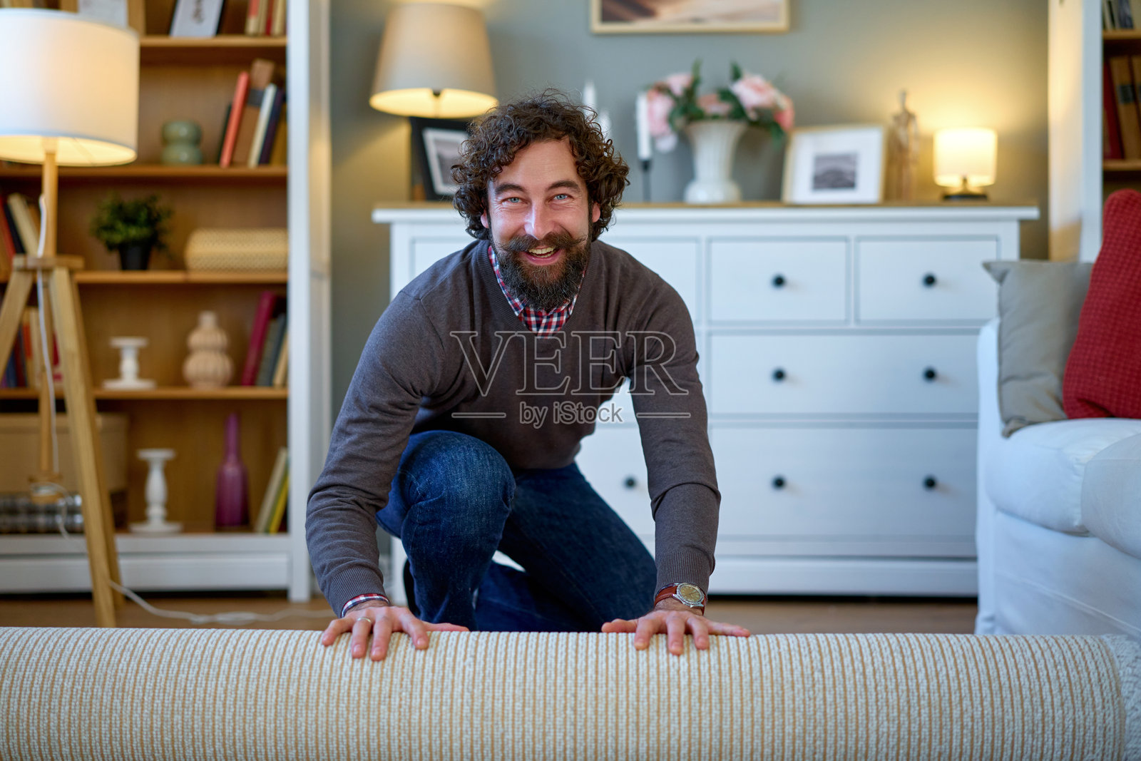 男人微笑着在地板上展开新地毯照片摄影图片