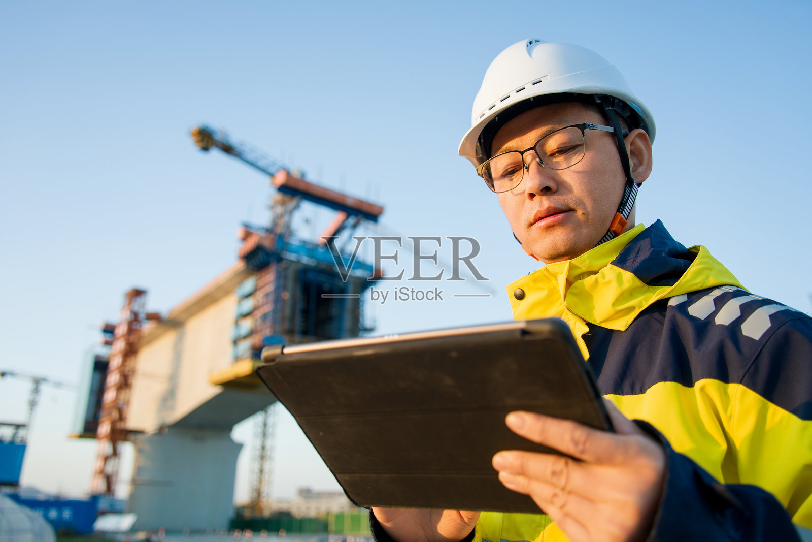 工程师戴安全帽持平板查看桥梁施工现场照片摄影图片