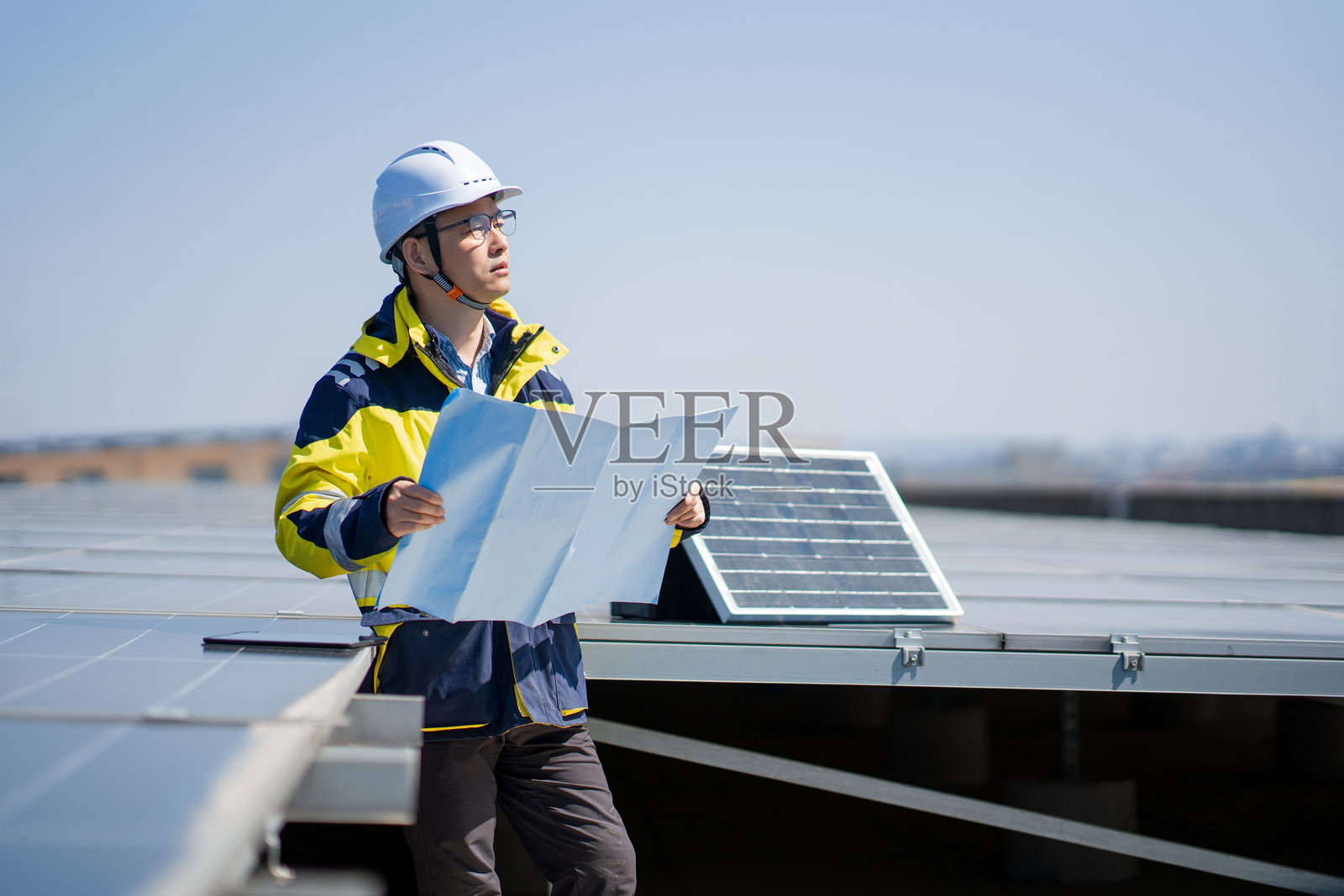 工程师屋顶检查光伏板并查看图纸照片摄影图片