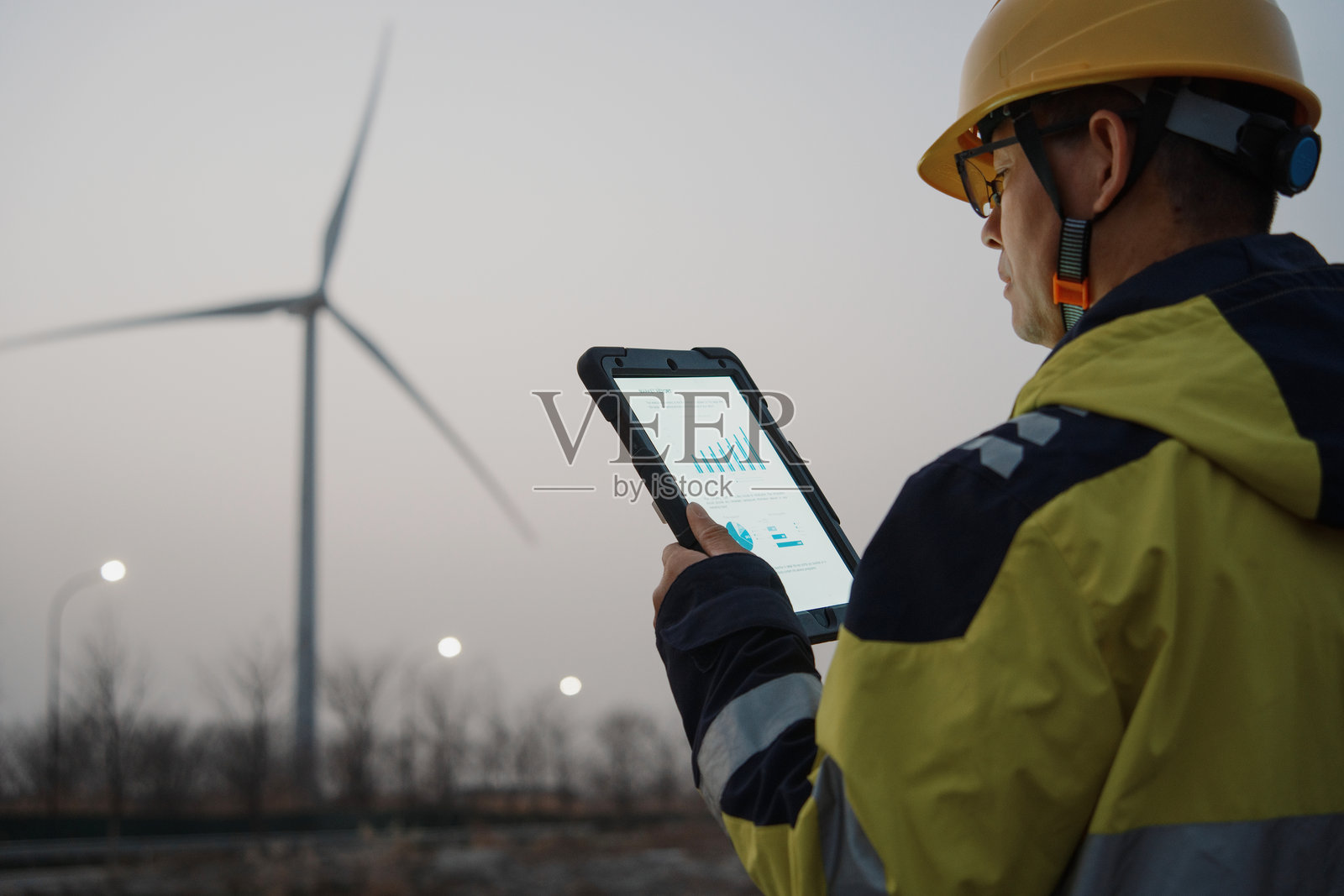 工程师戴安全帽持平板查看风电数据照片摄影图片