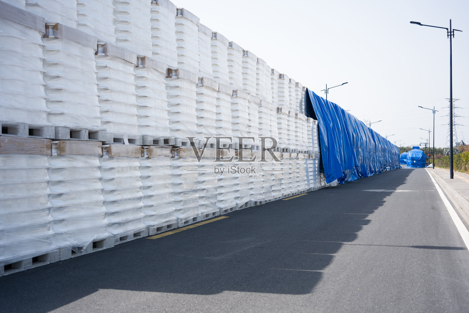道路旁堆叠白色塑料托盘与蓝色防雨布照片摄影图片