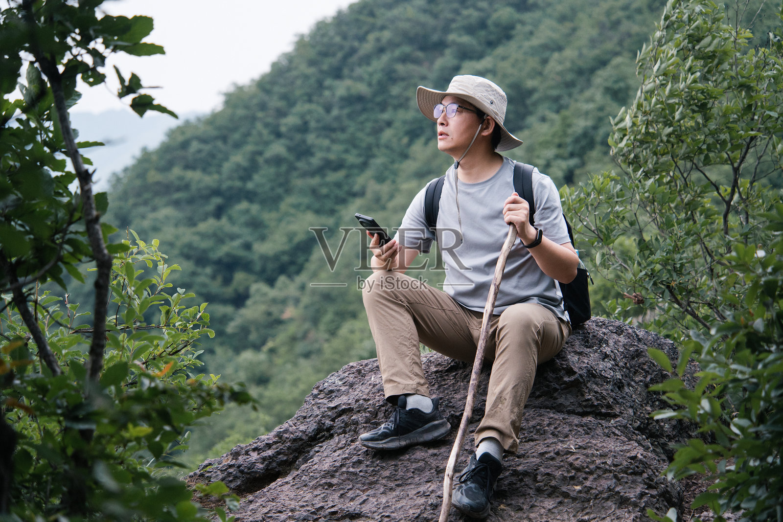 男子山间岩石休憩看手机照片摄影图片