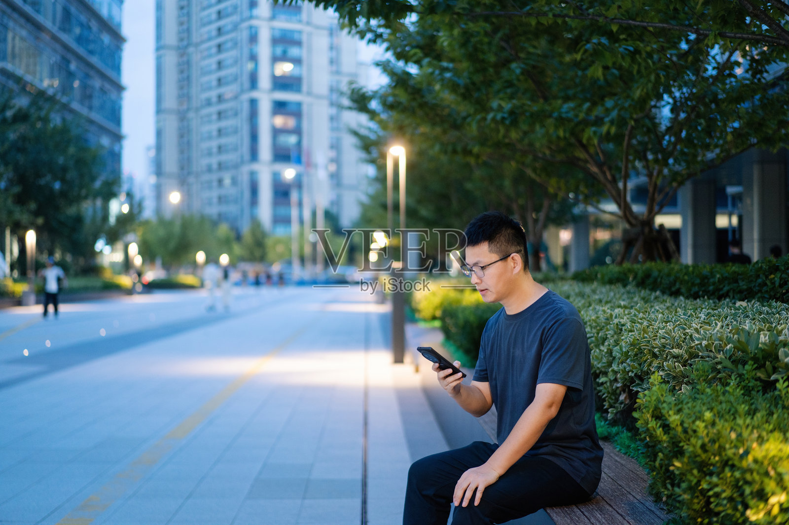 都市男子坐长椅看手机照片摄影图片