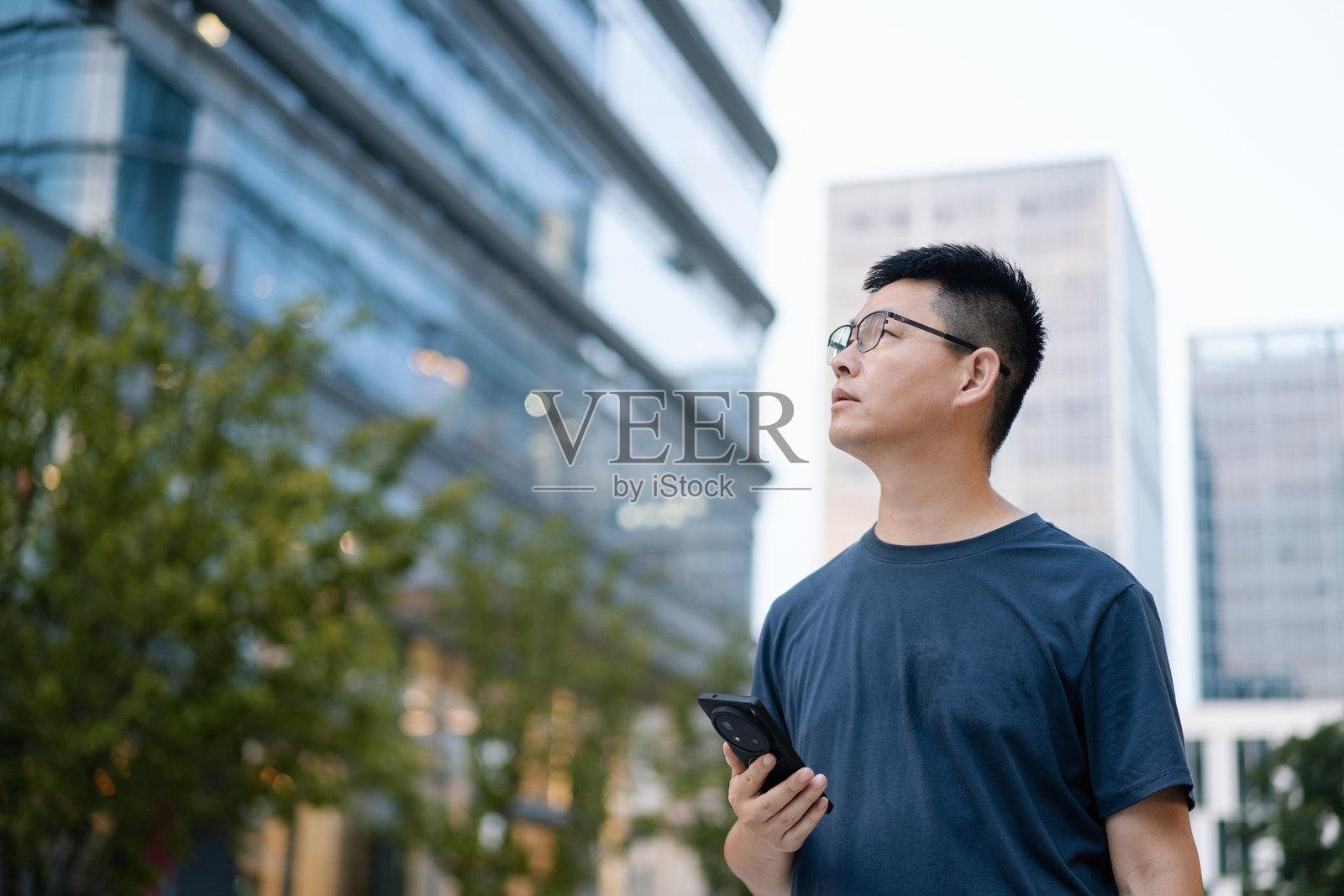 都市持手机男子望远方照片摄影图片