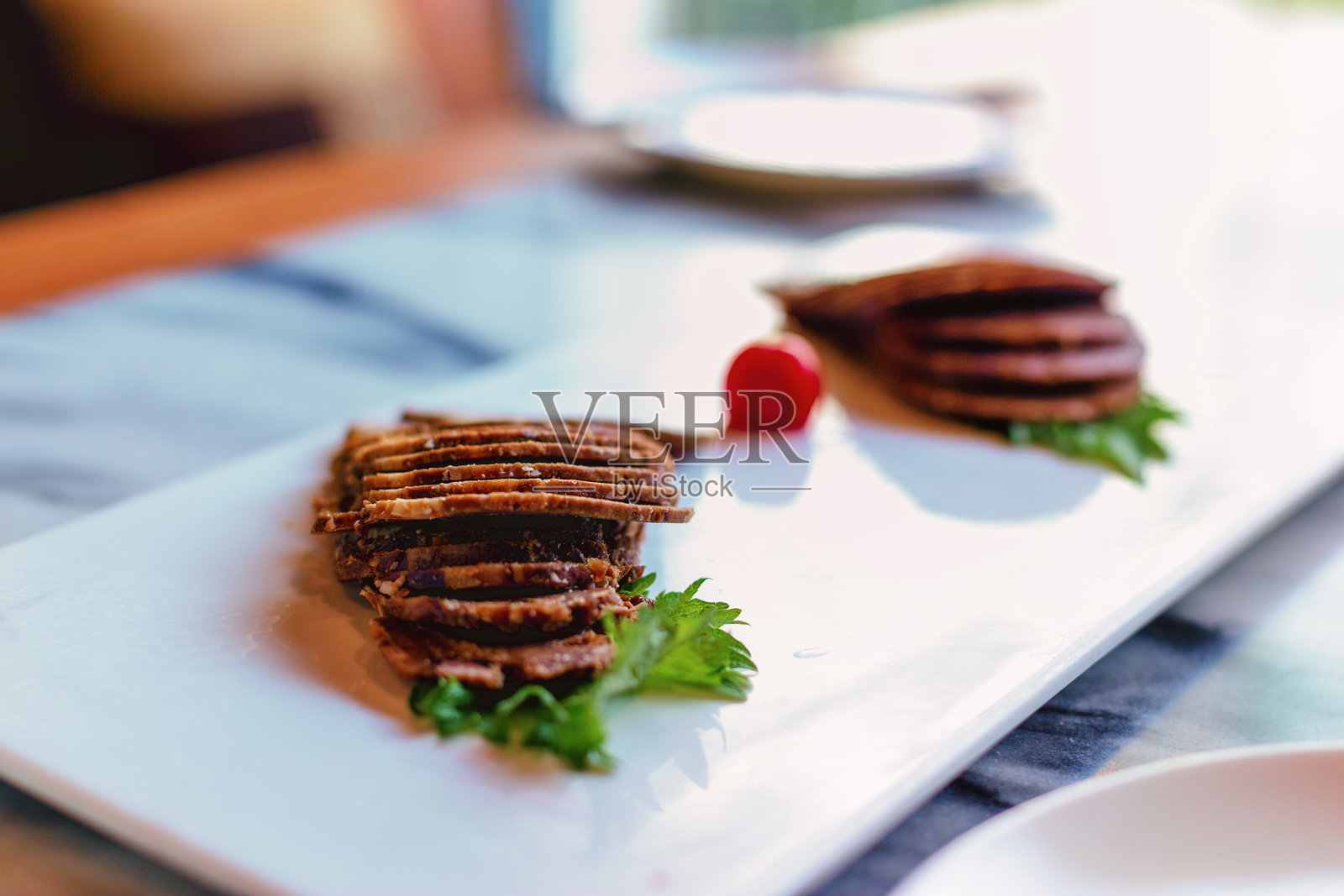 白色长盘上摆放两份切片牛肉配香菜与小番茄照片摄影图片