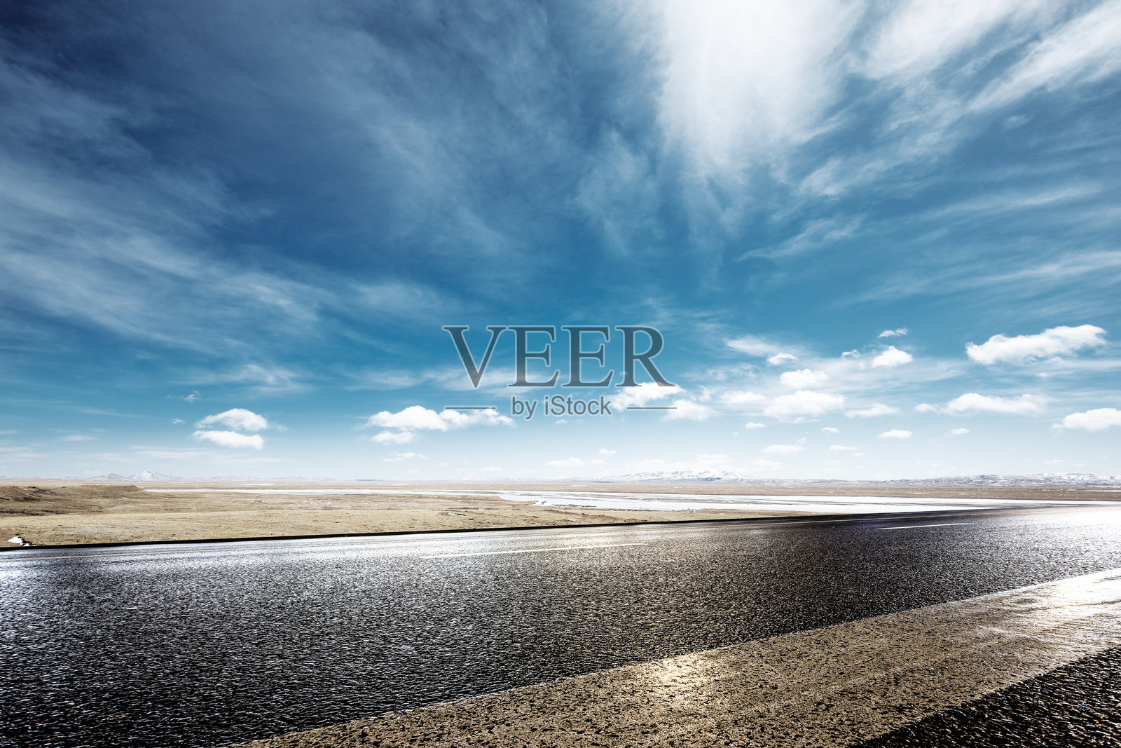 雨后湿润柏油公路延伸至辽阔草原与蓝天白云交界处照片摄影图片