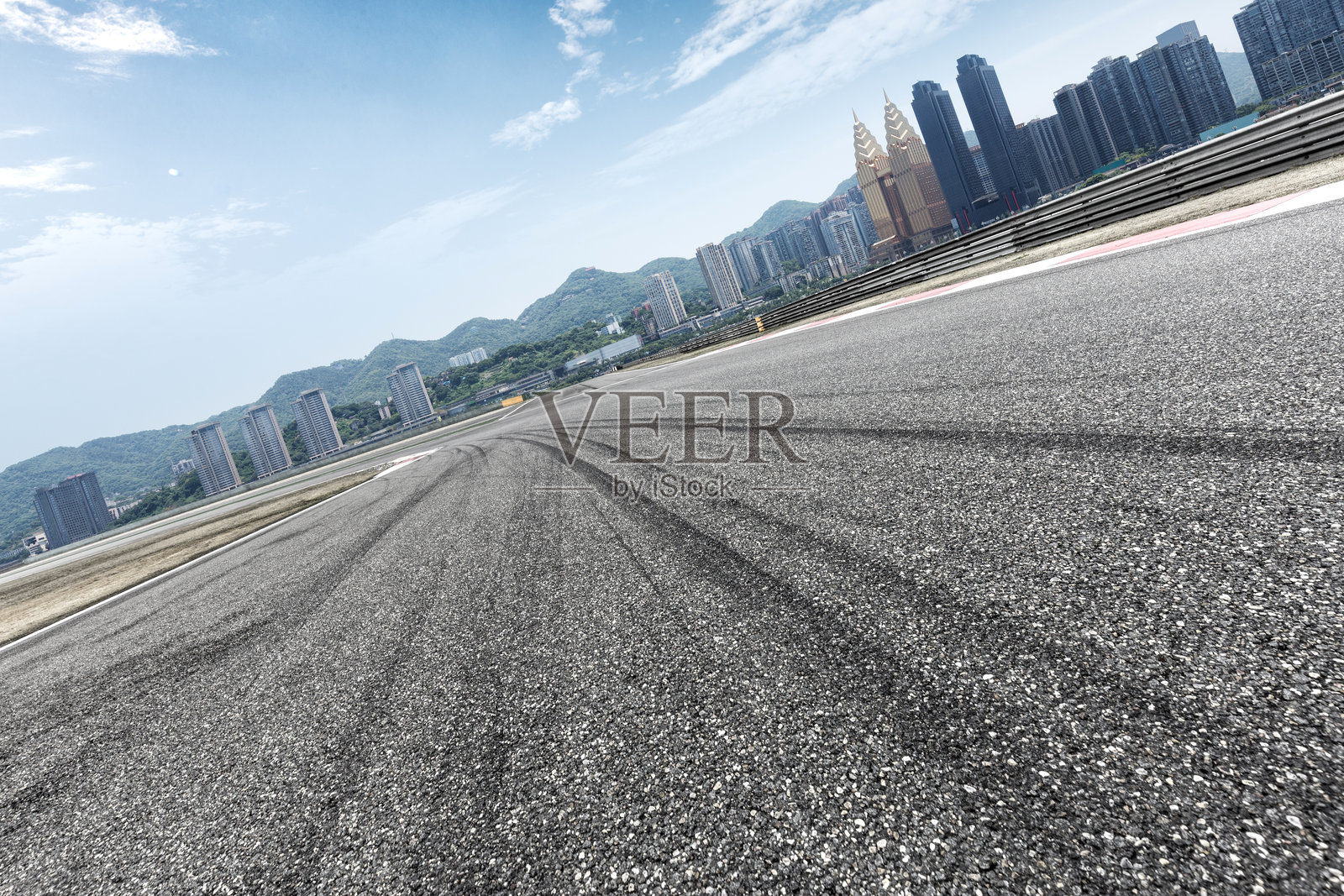城市赛道沥青路面轮胎痕迹与高楼山景背景照片摄影图片