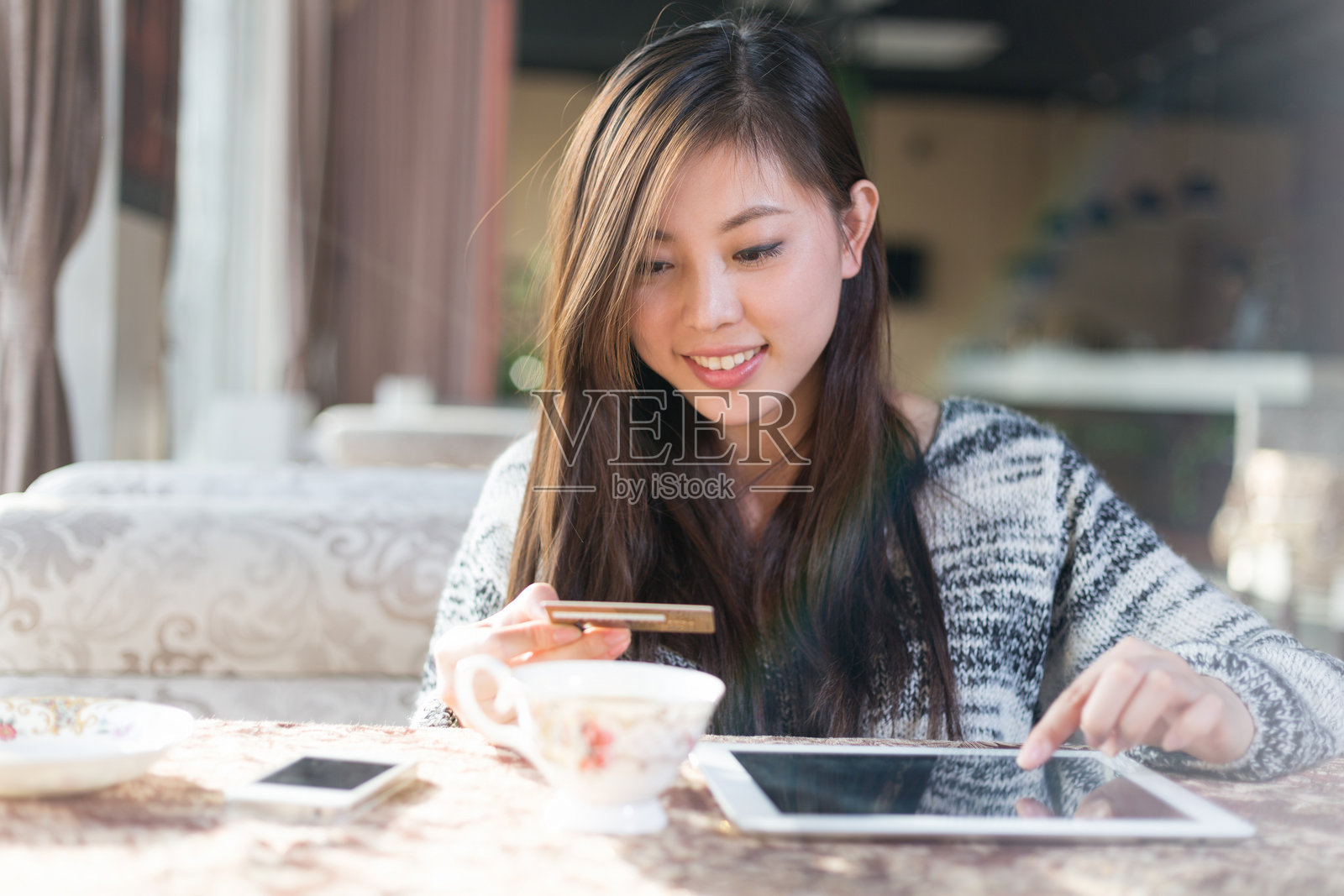 年轻女性在咖啡馆使用平板电脑和手机微笑照片摄影图片