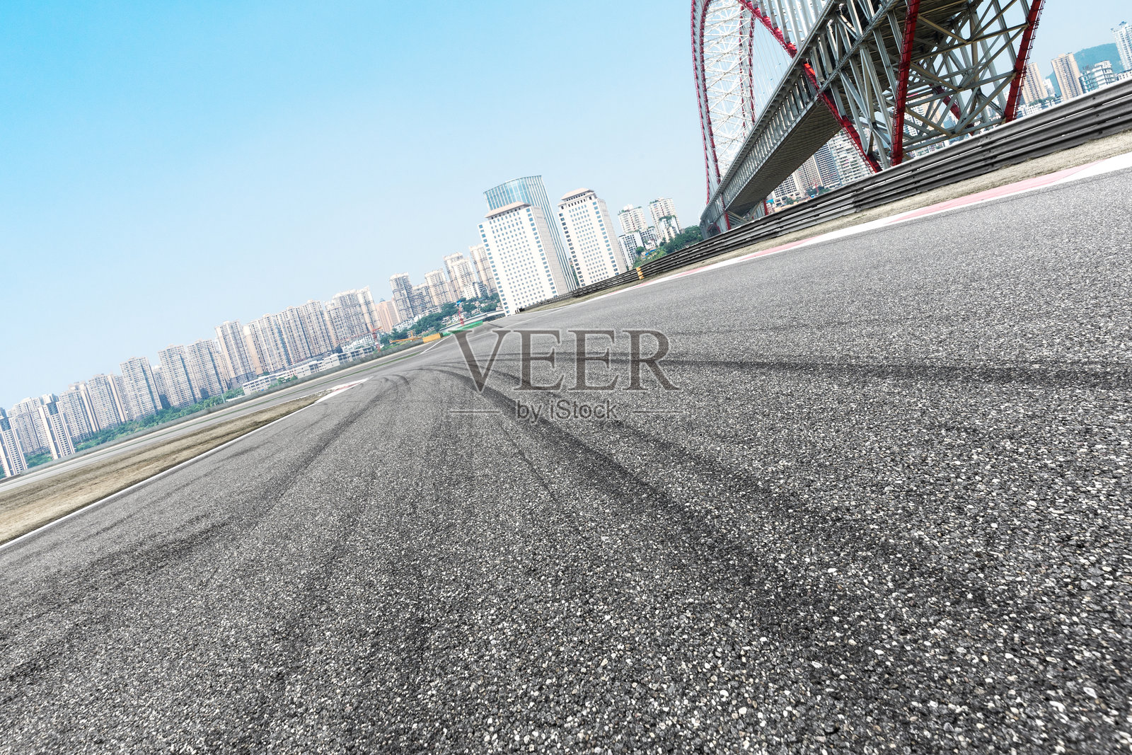 城市高架桥下空旷沥青赛道与远处高楼群照片摄影图片
