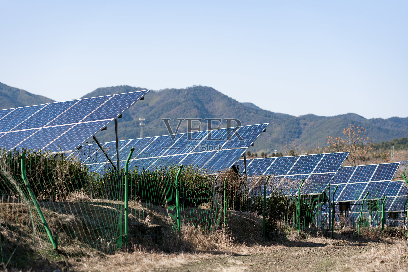 山地光伏电站阵列与绿色围栏景观照片摄影图片