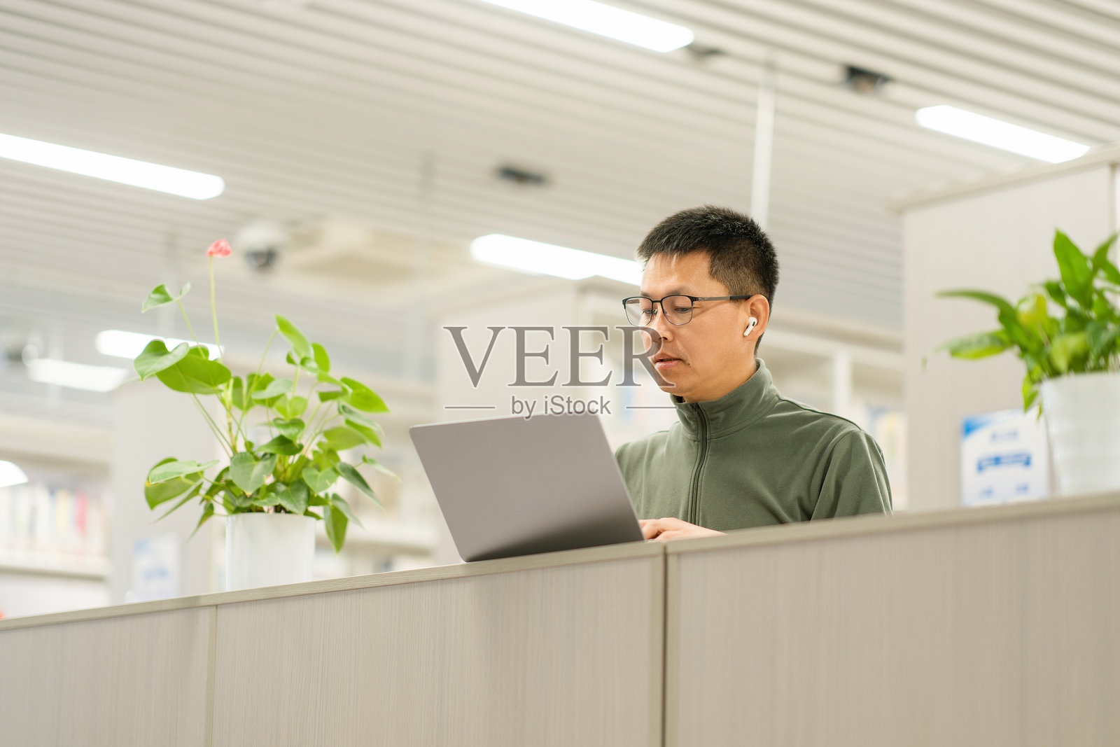 戴眼镜男子在图书馆隔间使用笔记本电脑照片摄影图片