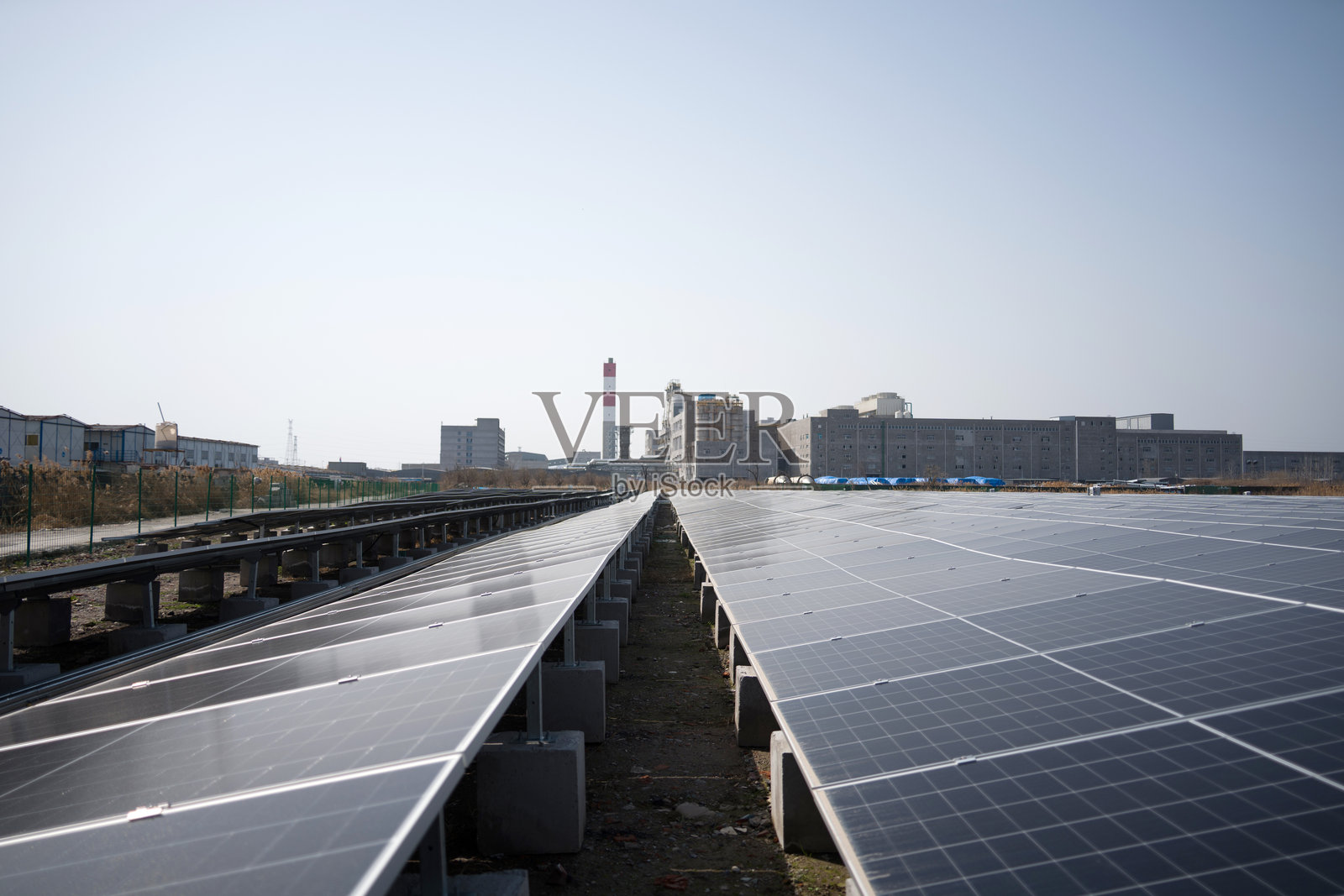 工业区屋顶光伏阵列与远处厂房烟囱照片摄影图片