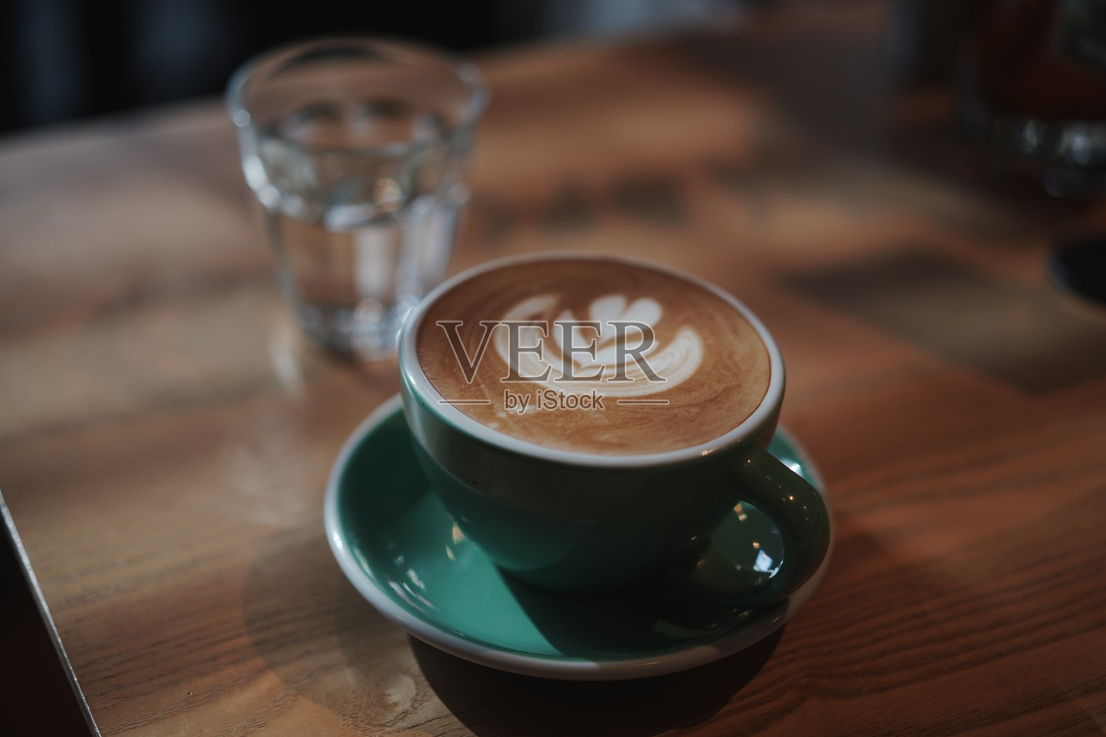 木质桌面上绿色咖啡杯拉花特写照片摄影图片