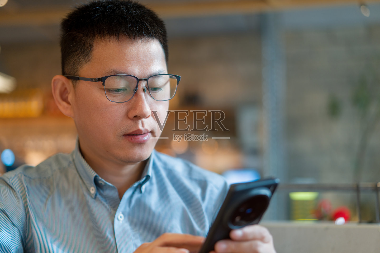 戴眼镜男子专注看手机屏幕照片摄影图片