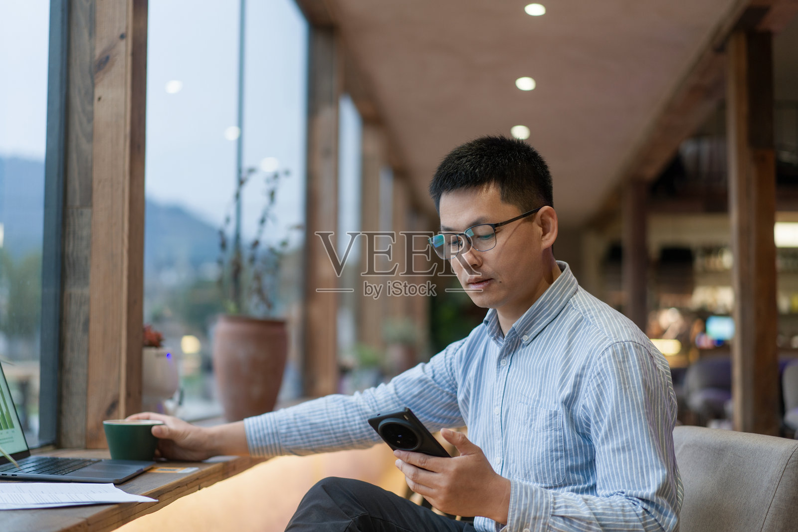 戴眼镜男子咖啡馆用手机看屏幕照片摄影图片