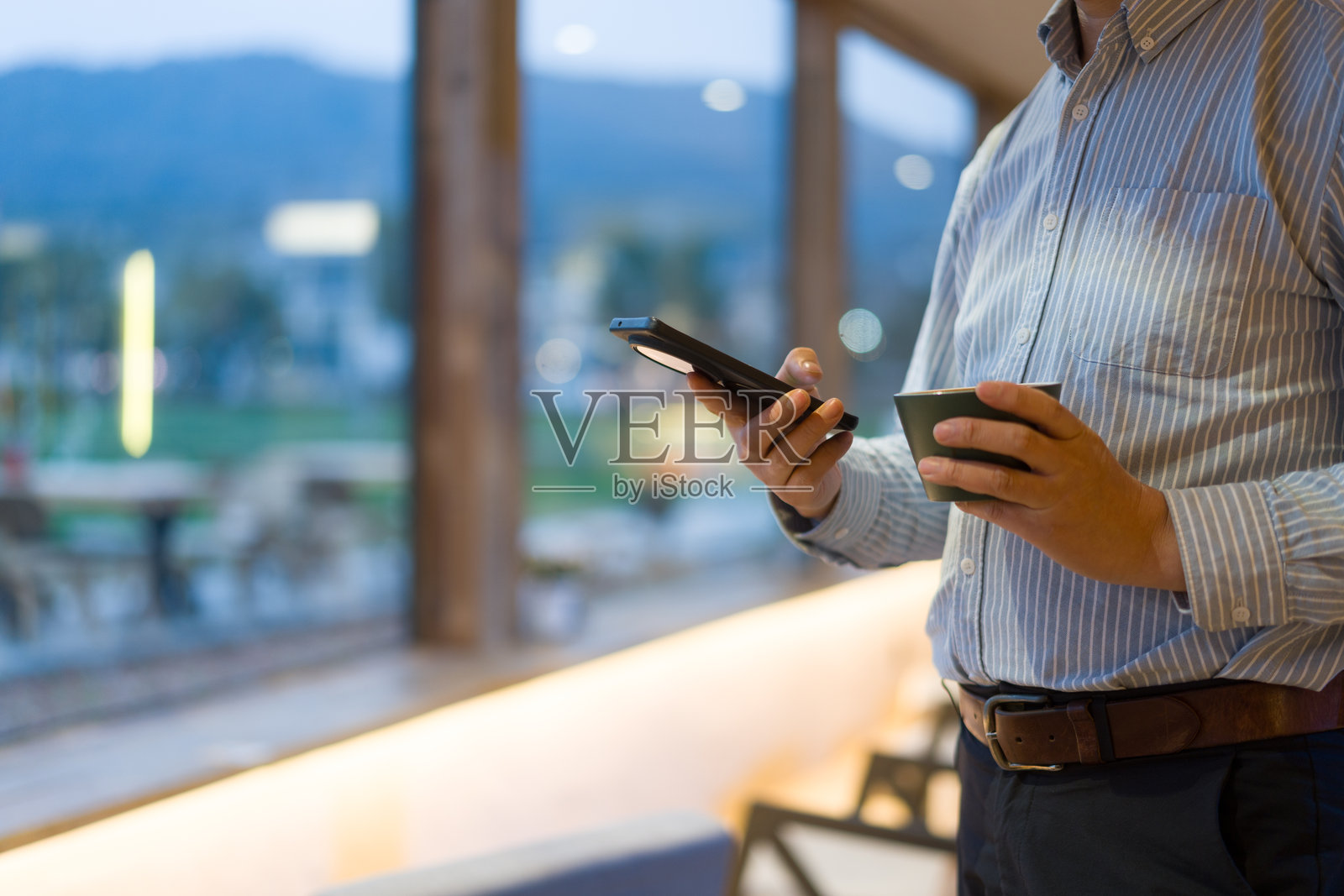 商务男士手持手机咖啡杯室内场景照片摄影图片