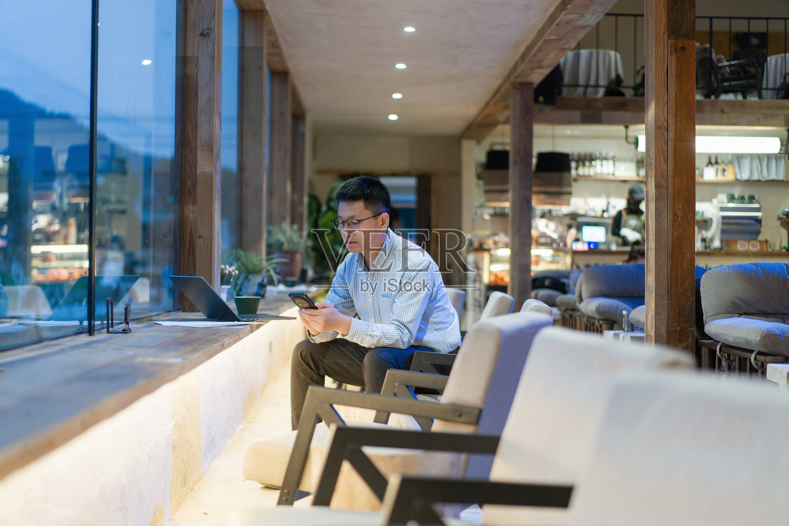戴眼镜男子咖啡馆窗边使用手机照片摄影图片