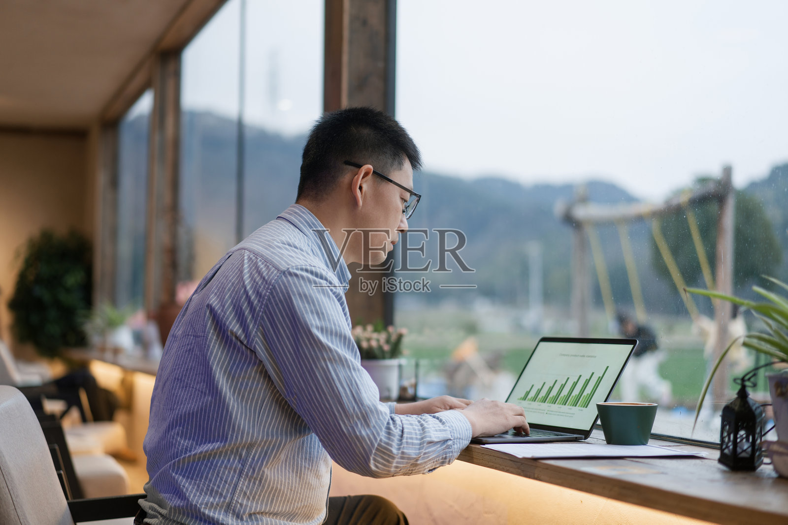戴眼镜男子窗边用笔记本电脑工作照片摄影图片