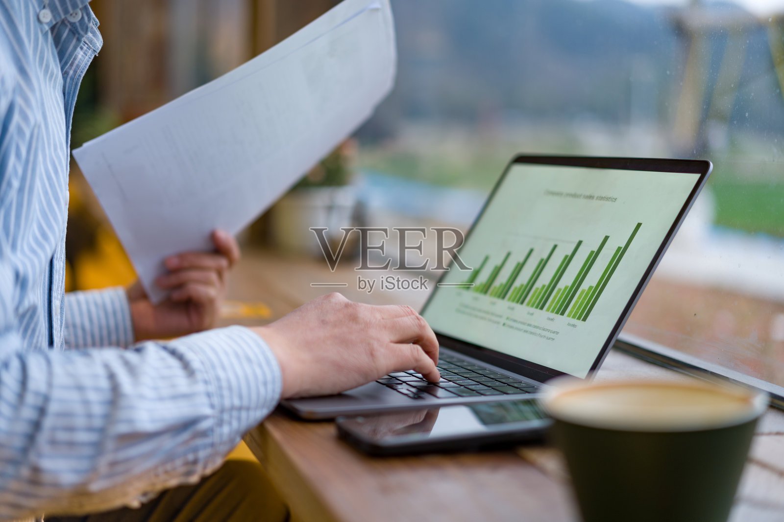 办公桌前男子手持文件操作笔记本电脑照片摄影图片