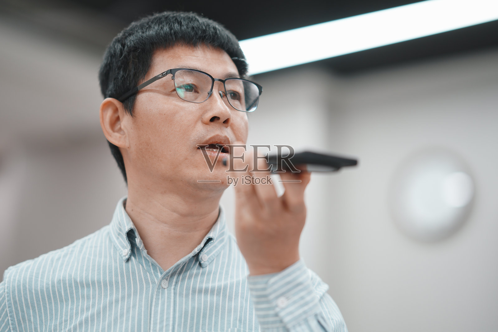 戴眼镜中年男子手持手机语音输入照片摄影图片