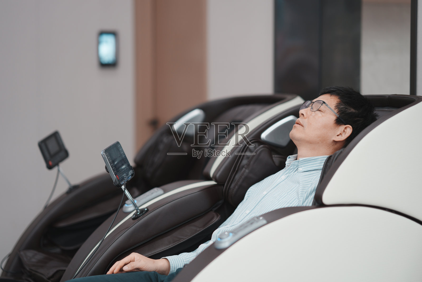 中年男子戴眼镜躺按摩椅放松休息照片摄影图片